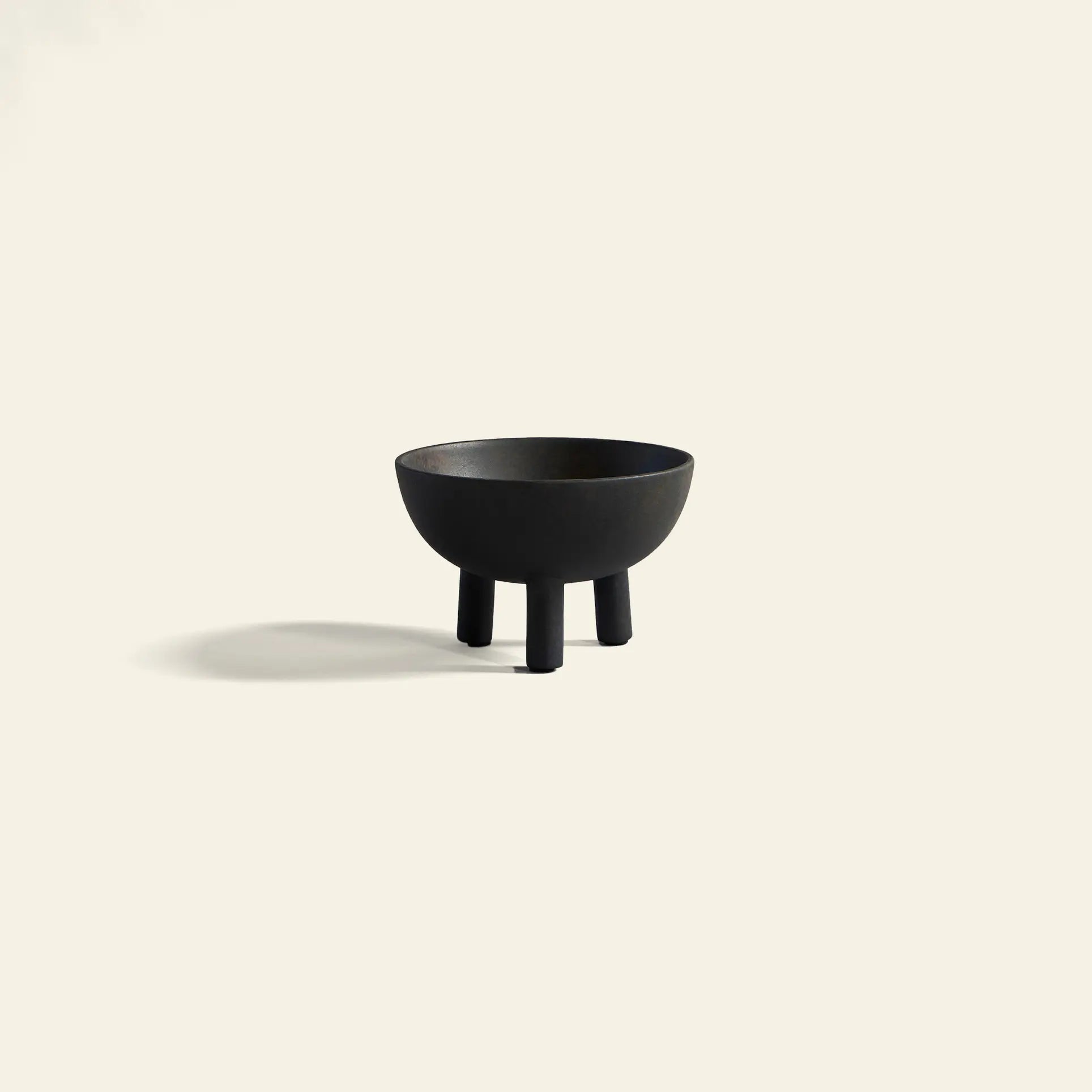 The 101 Copenhagen Duck Bowl, Big by 101 Copenhagen features a minimalist black ceramic design with three short legs, standing on a light beige background and casting a soft shadow—an ideal piece for Scandinavian-inspired interiors.