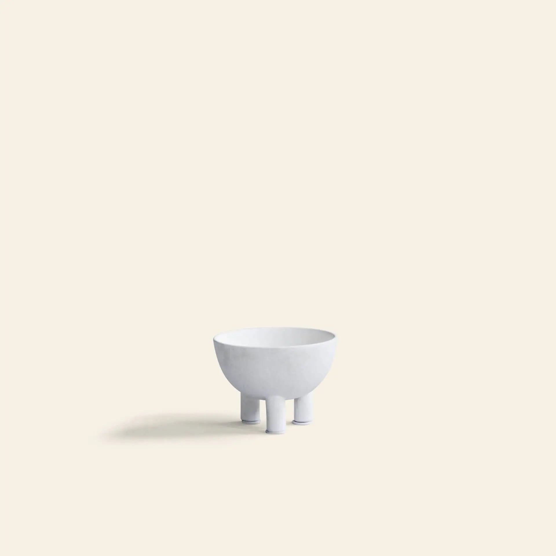 The 101 Copenhagen Duck Bowl, Mini features a minimalist white design with three short legs, casting a soft left shadow on a neutral background—an elegant modern accent from 101 Copenhagen for your decor.