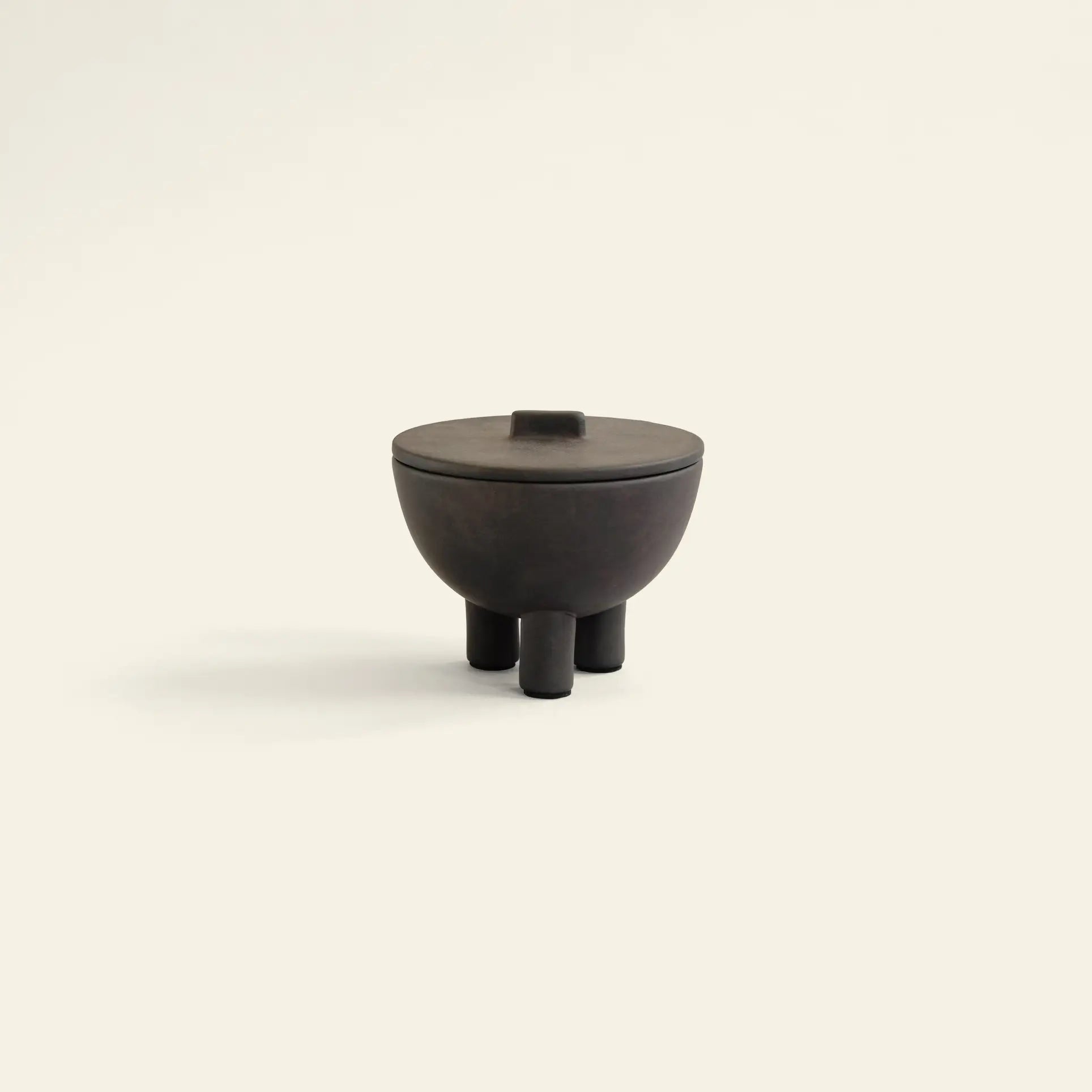 The 101 Copenhagen Duck Jar, Medio by 101 Copenhagen is a small, dark hand-glazed jar with a round lid and three cylindrical legs—ideal as a decorative storage piece—shown here against a light background.