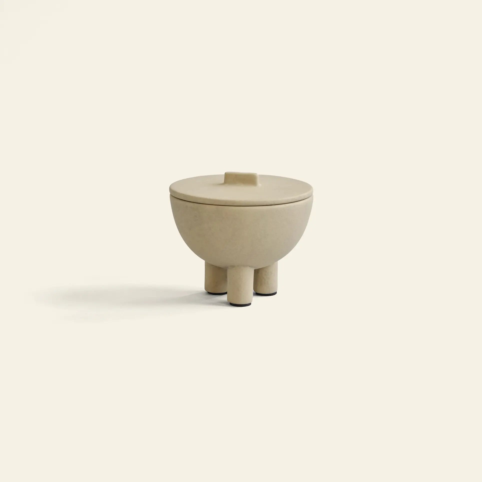 The 101 Copenhagen Duck Jar, Medio by 101 Copenhagen is a small, beige, round jar with a lid and three short legs, hand-glazed for a smooth finish—ideal for decorative storage in any space.