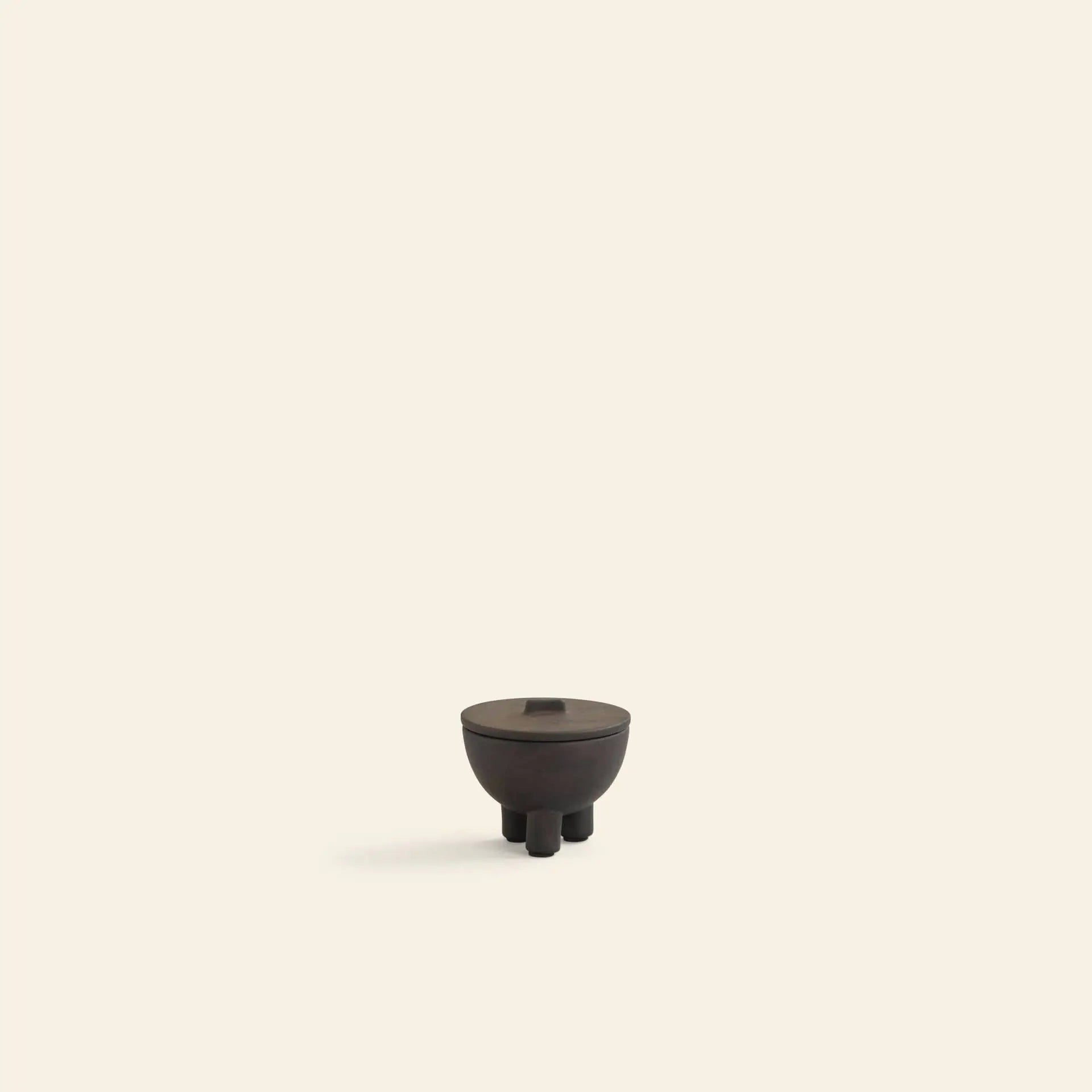 The 101 Copenhagen Duck Jar, Mini by 101 Copenhagen is a small, dark brown round jar with a lid and three legs, centered on a light beige background—an elegant decorative accent for any space.