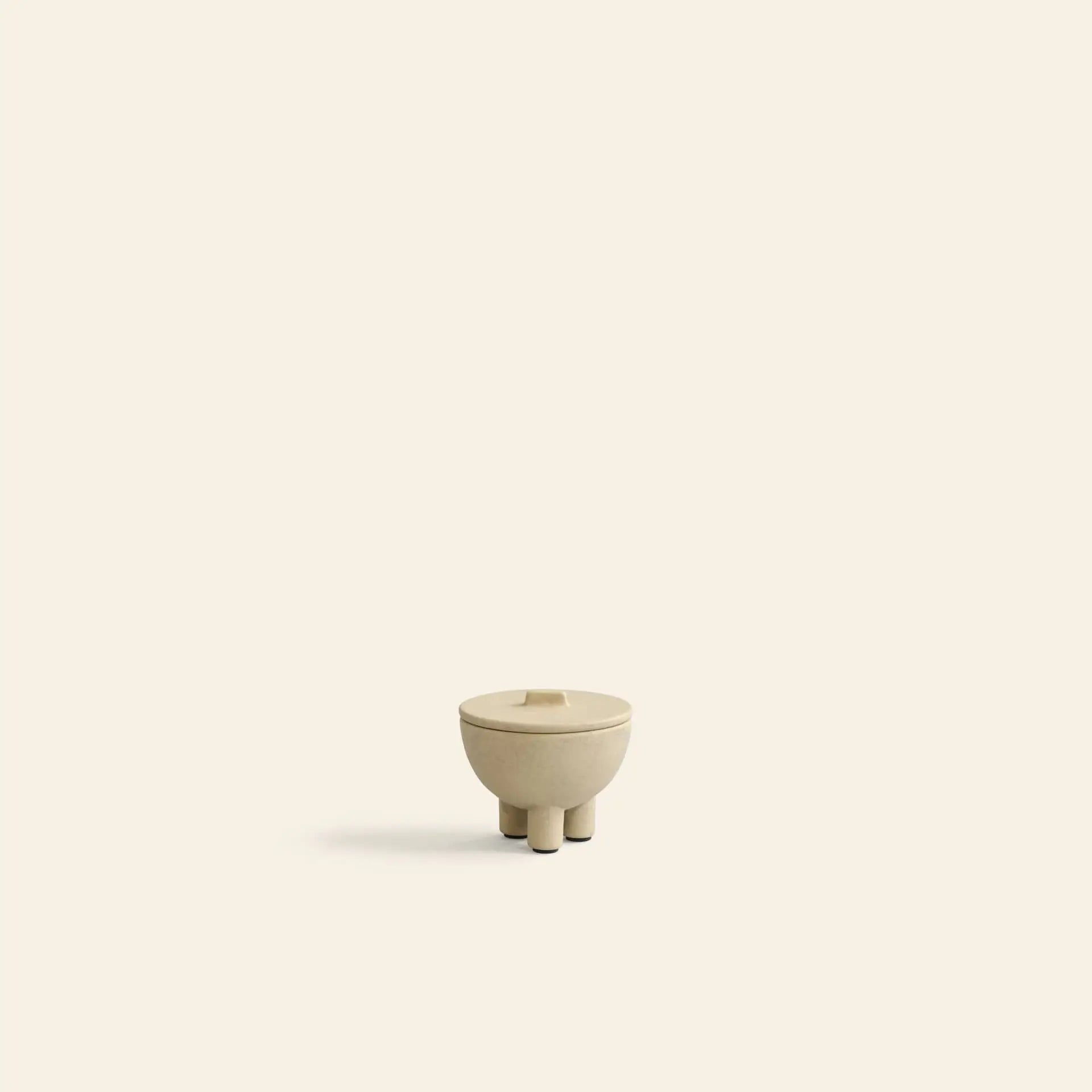 The 101 Copenhagen Duck Jar, Mini by 101 Copenhagen is a small, beige, round jar with three short legs and a fitted lid, centered on a light beige background—ideal as decorative accent or for storage.