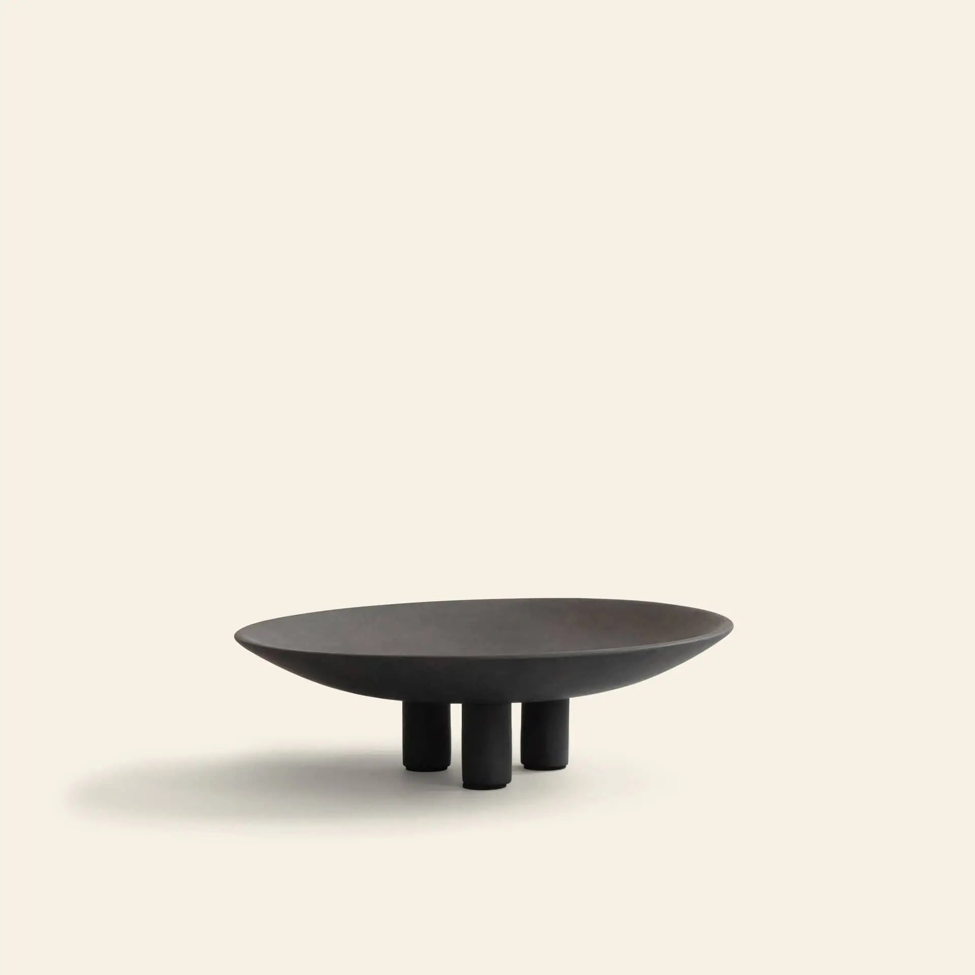 The 101 Copenhagen Duck Plate, Mini by 101 Copenhagen features a minimalist dark design with three short cylindrical legs, set against a plain light beige background—perfect for modern home decor.