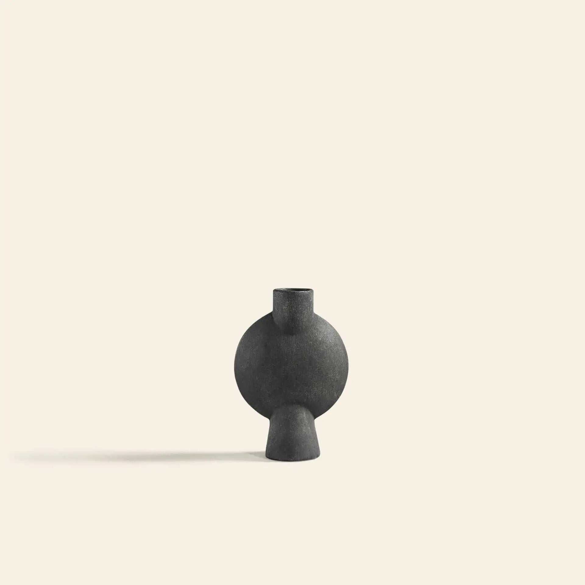 The 101 Copenhagen Sphere Vase Bubl, Mini is a small, round black ceramic vase with a sculptural shape and narrow neck, shown against an off-white background. It casts a soft left shadow—ideal for modern décor.