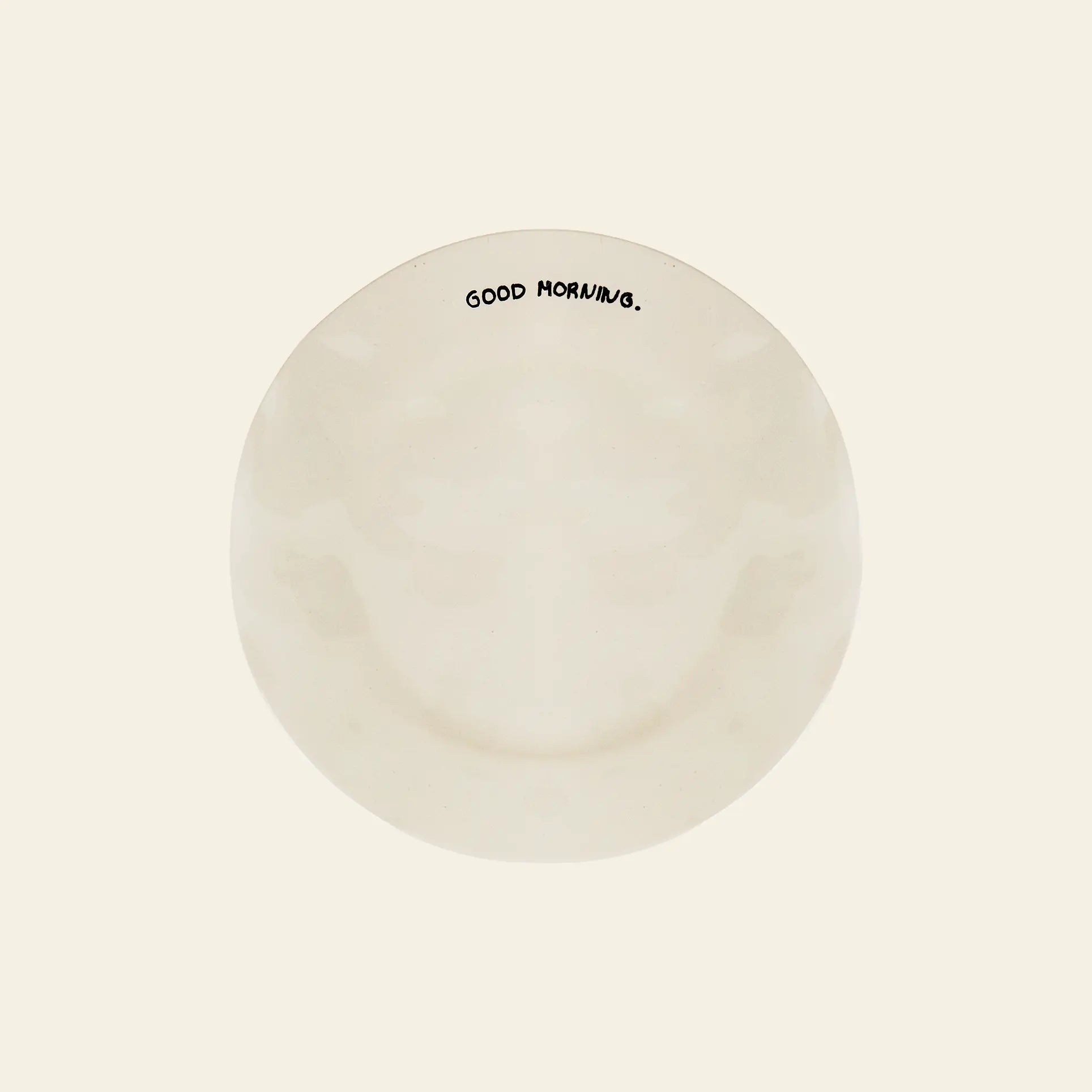 The Anna + Nina Good Morning Breakfast Plate by Anna + Nina features “GOOD MORNING.” in black near the rim, viewed from above on a plain off-white background—a cheerful upgrade to your breakfast routine.