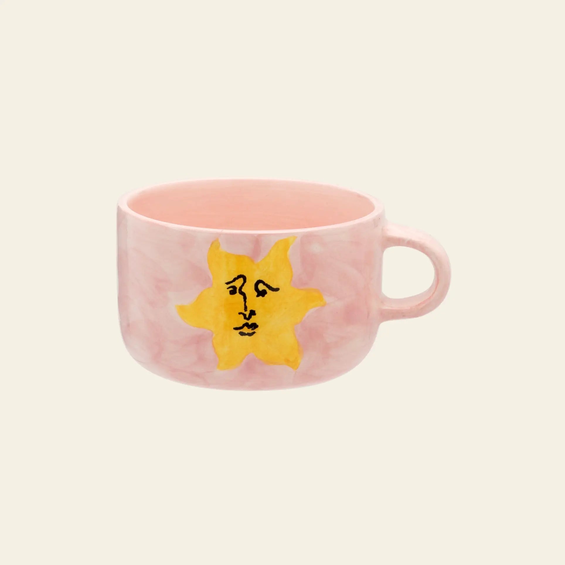 The Anna + Nina Sunny Side Up Cappuccino Mug features a pink marbled texture, a yellow sun with a stylized face, and a simple handle—perfect for brightening your coffee moments.