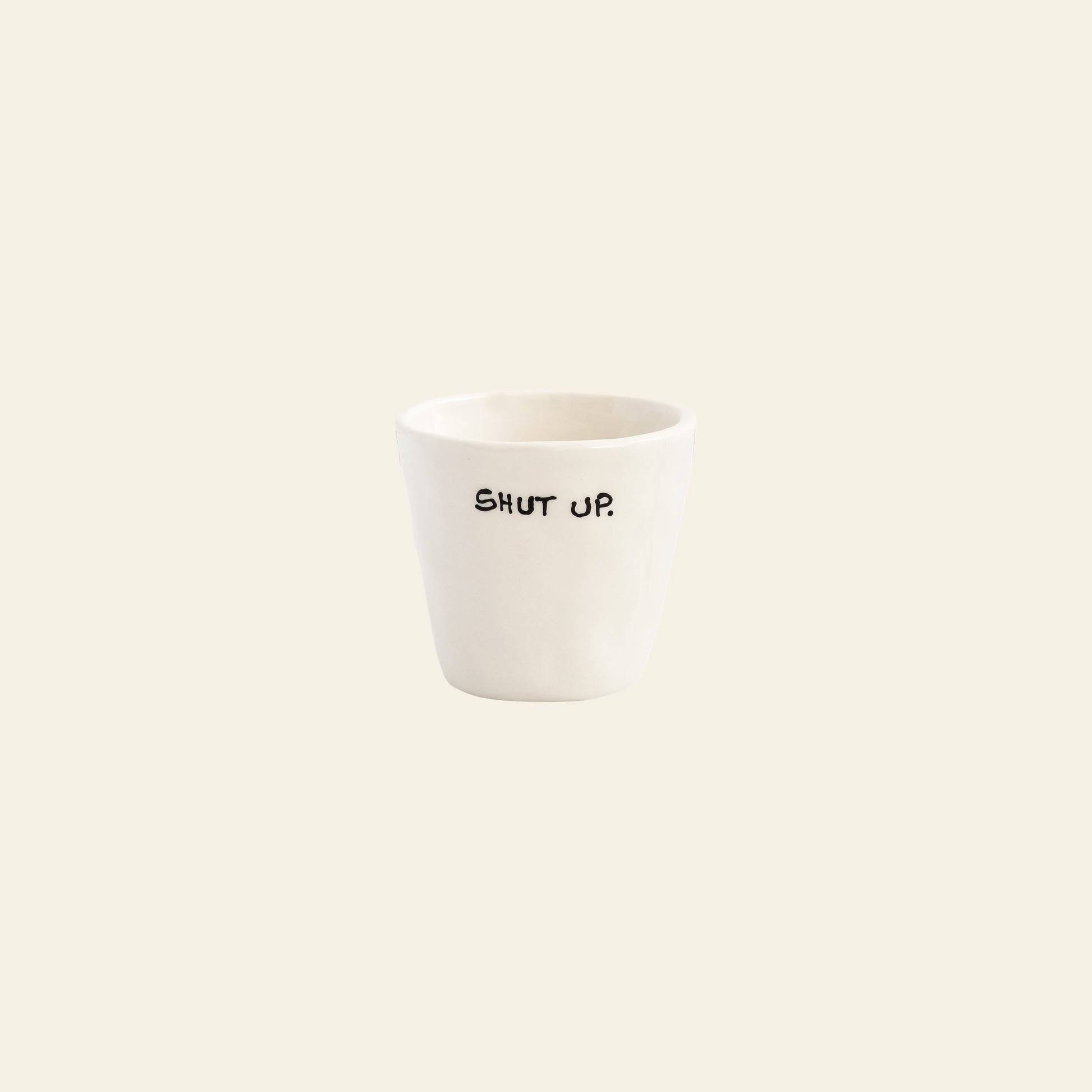 The Anna + Nina Shut Up Espresso Cup is a small white ceramic cup with “SHUT UP.” printed in black—perfect for your morning routine or an essential caffeine boost. Brand: Anna + Nina.