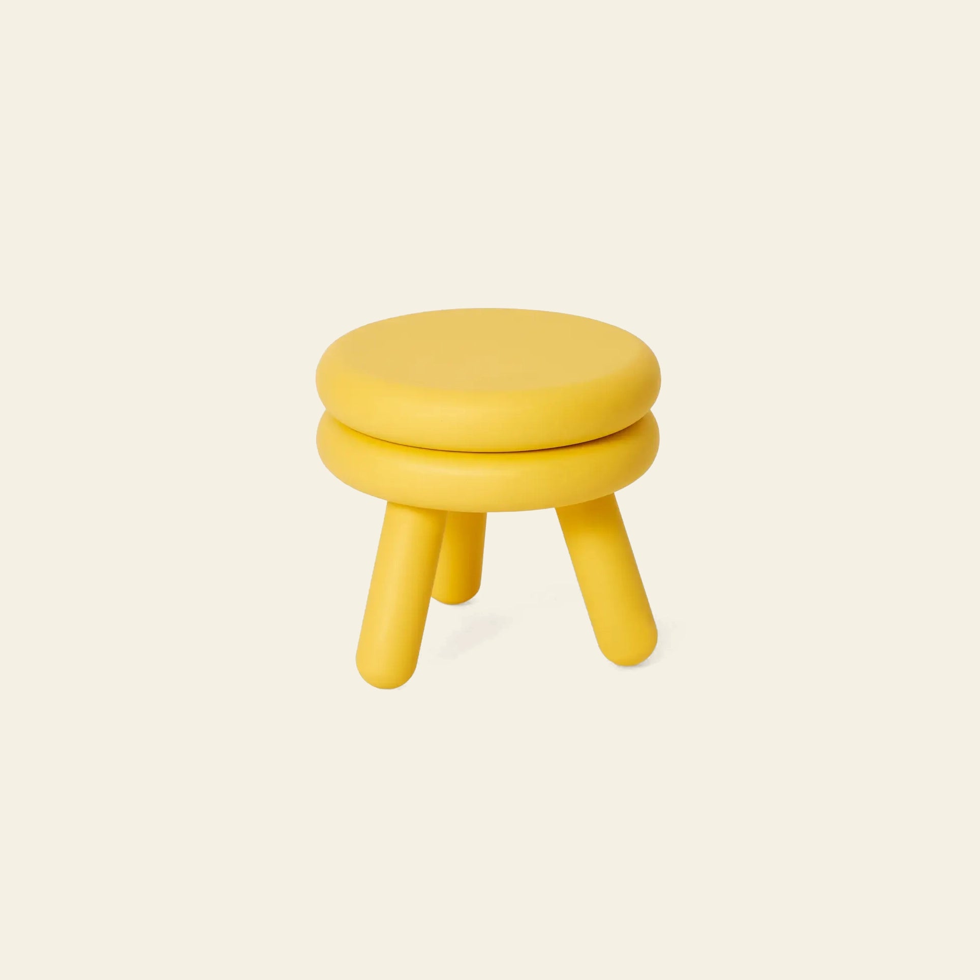 The Areaware Pluma Stool Short by Areaware is a small, round, bright yellow stool with three cylindrical legs and a cushioned seat. Its contemporary design enhances versatility in any modern space, shown here against a light beige background.