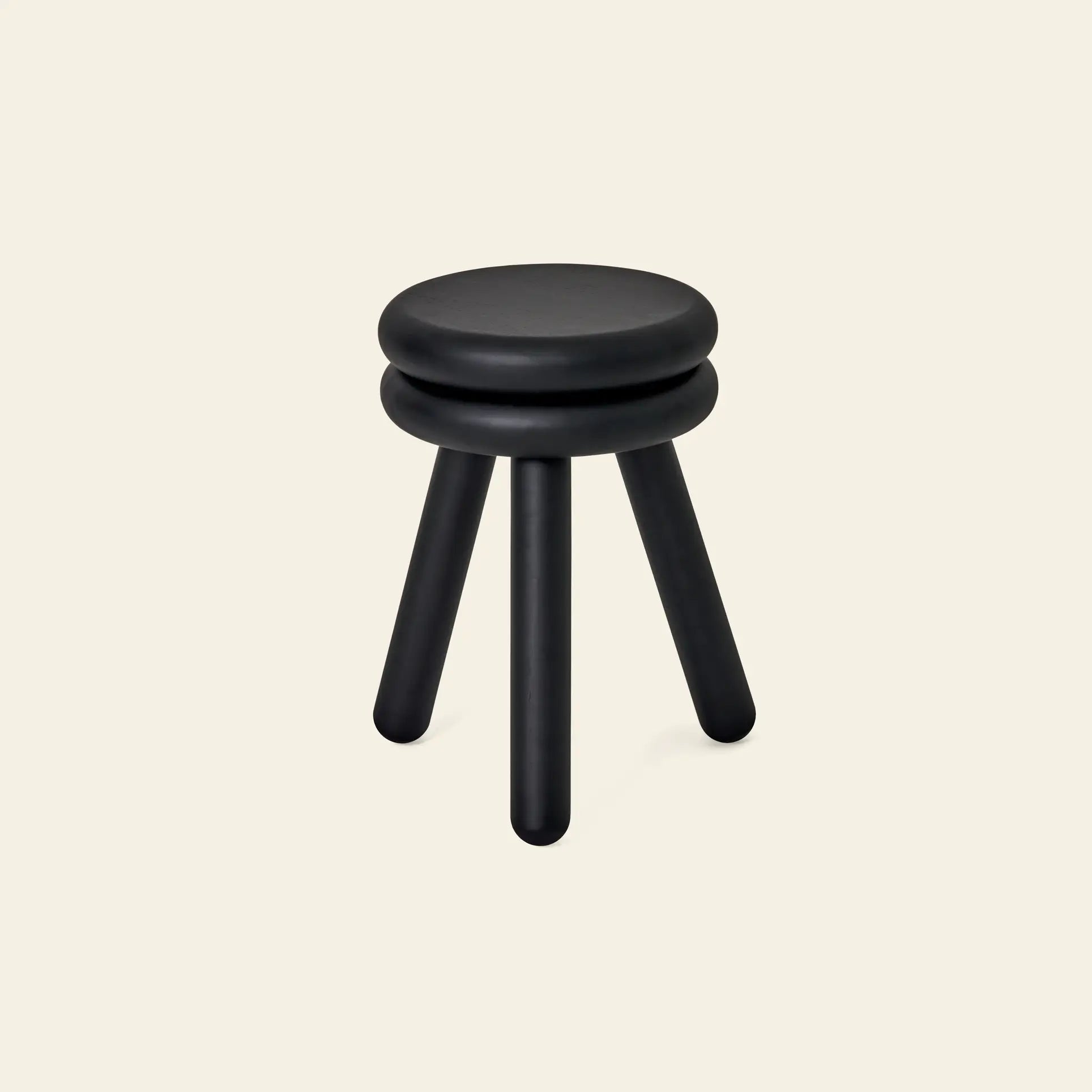 The Areaware Pluma Stool Tall by Areaware is a modern black stool featuring a round, double-layered seat and three cylindrical legs, shown against a plain light beige background.