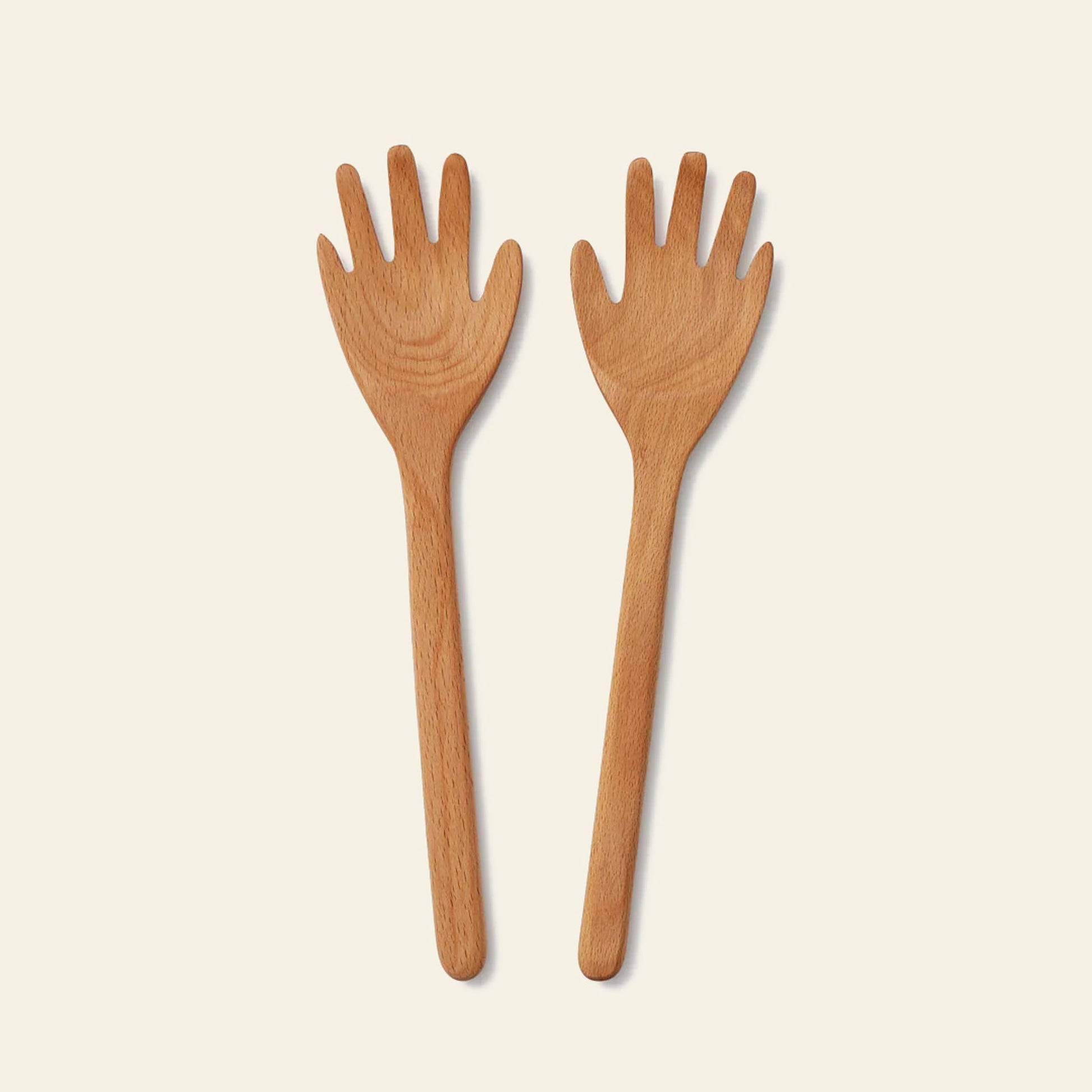 The Areaware Serving Friends - Hands by Areaware are wooden salad servers shaped like hands with carved fingers, adding a playful touch to your dining table.