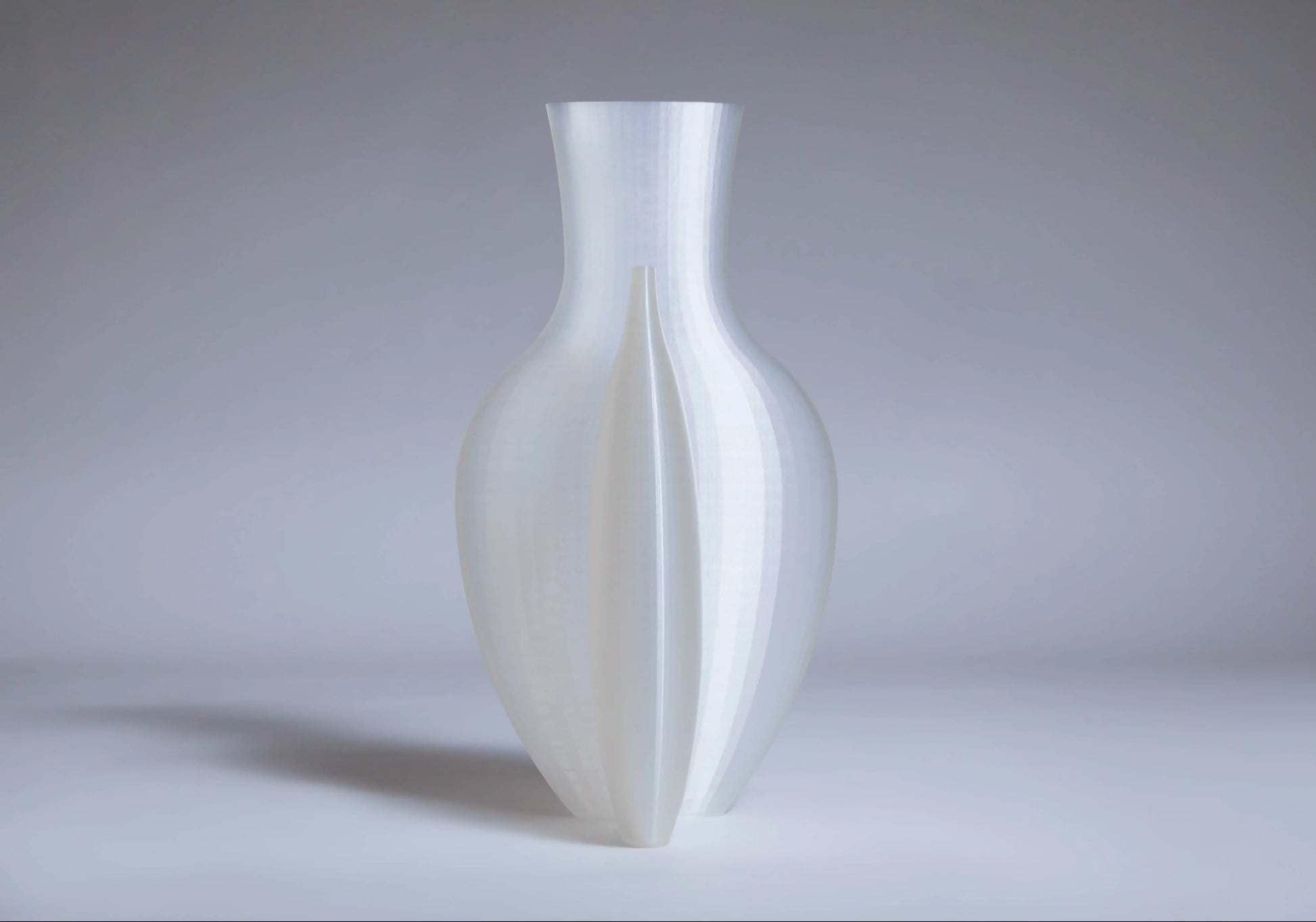 The Argot Studio Double Vessel, by Argot Studio, is a translucent white vase with a smooth 3D-printed surface and symmetrical vertical grooves, elegantly blending modern style with classic design influences.