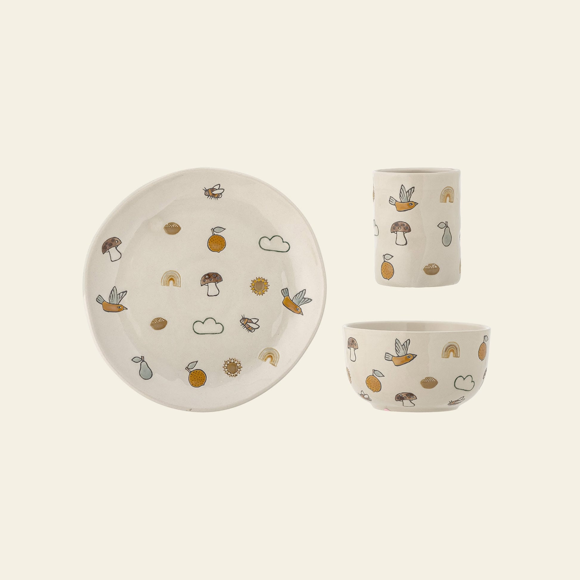 The Bloomingville Agnes Tableware Set by Bloomingville is a handmade ceramic set featuring a plate, bowl, and cup with hand-engraved mushrooms, rainbows, birds, and fruits on a cream background for unique charm.