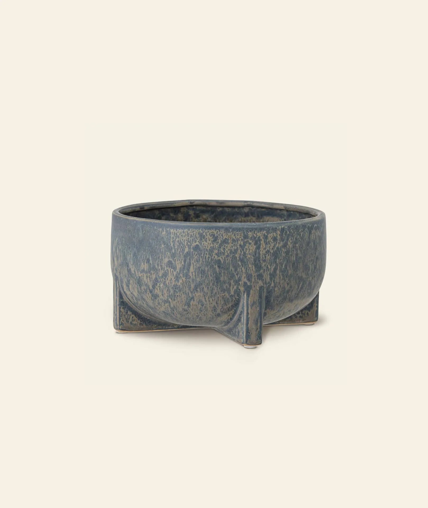 The Bloomingville Beryl Flowerpot by Bloomingville is a round, blue-gray pot with a textured finish and four short legs, ideal for greenery or decor. Photographed against an off-white background.