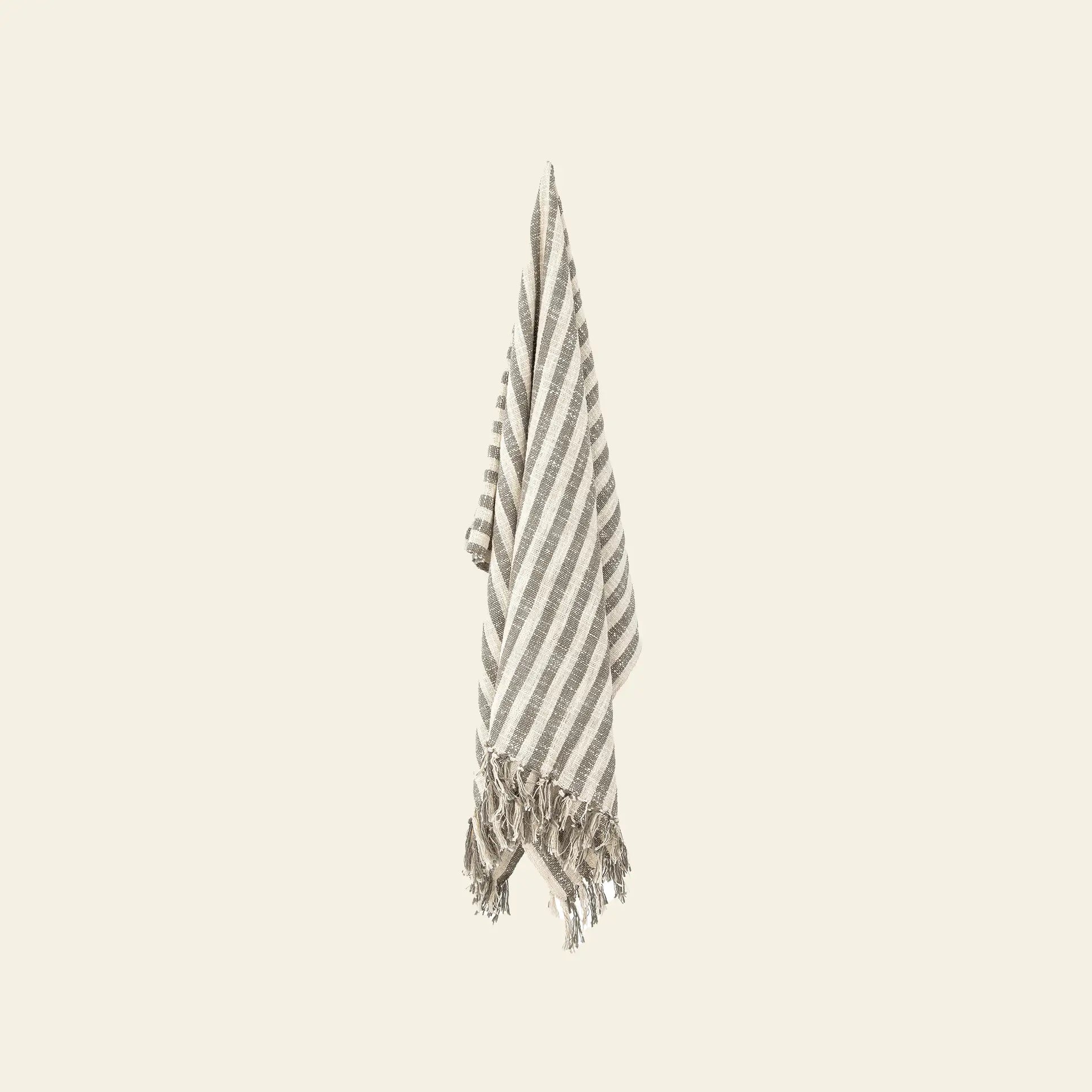 The Bloomingville Binnur Throw from Bloomingville, featuring beige and white stripes and fringed edges, is crafted from woven cotton and displayed against a light background.