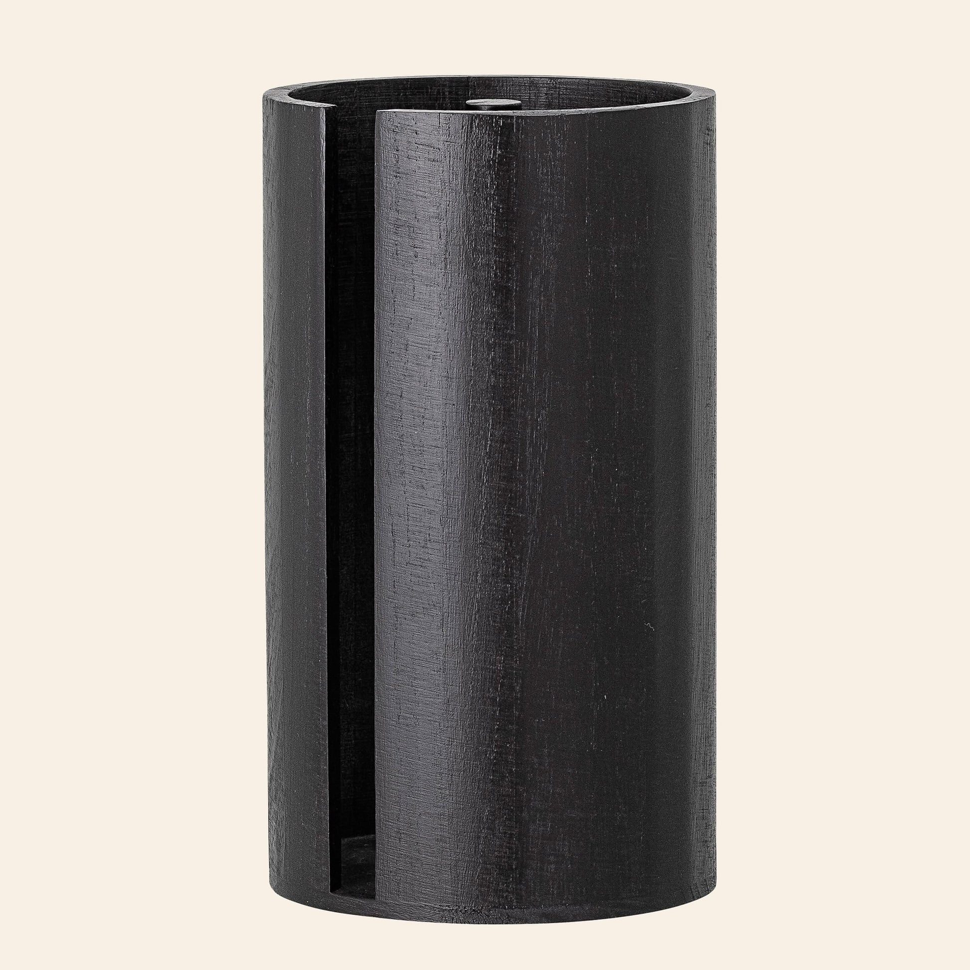 The Bloomingville Celian Kitchen Paper Stand by Bloomingville is a tall, cylindrical piece in dark paulownia wood with an open vertical slot and visible wood grain, exuding Scandinavian style against a plain light background.