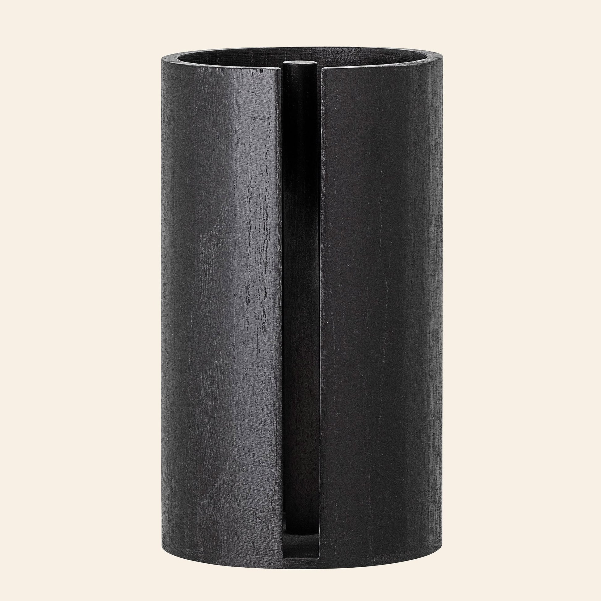 The Bloomingville Celian Kitchen Paper Stand by Bloomingville is a tall, cylindrical black paulownia wood stand with a vertical slit design, exuding Scandinavian elegance against a plain, light background.
