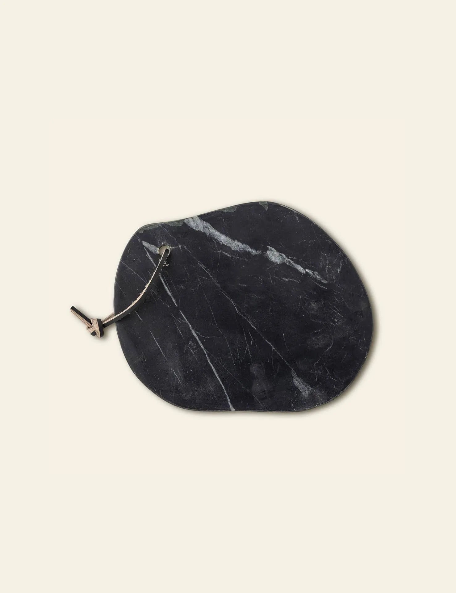 The Bloomingville Daris Cutting Board is a black marble cheese board with white veining, an attached metal slicer, and a smooth surface, set against a plain light background.