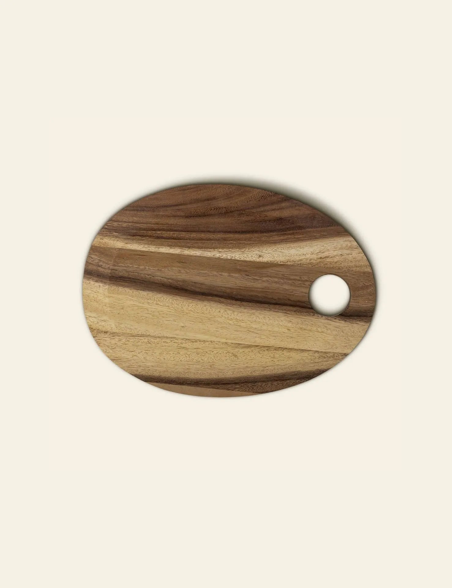 The Bloomingville Guti Cutting Board features oval suar wood with light and dark grains and a round hole near the edge, making it a stylish kitchen accessory. Brand: Bloomingville.