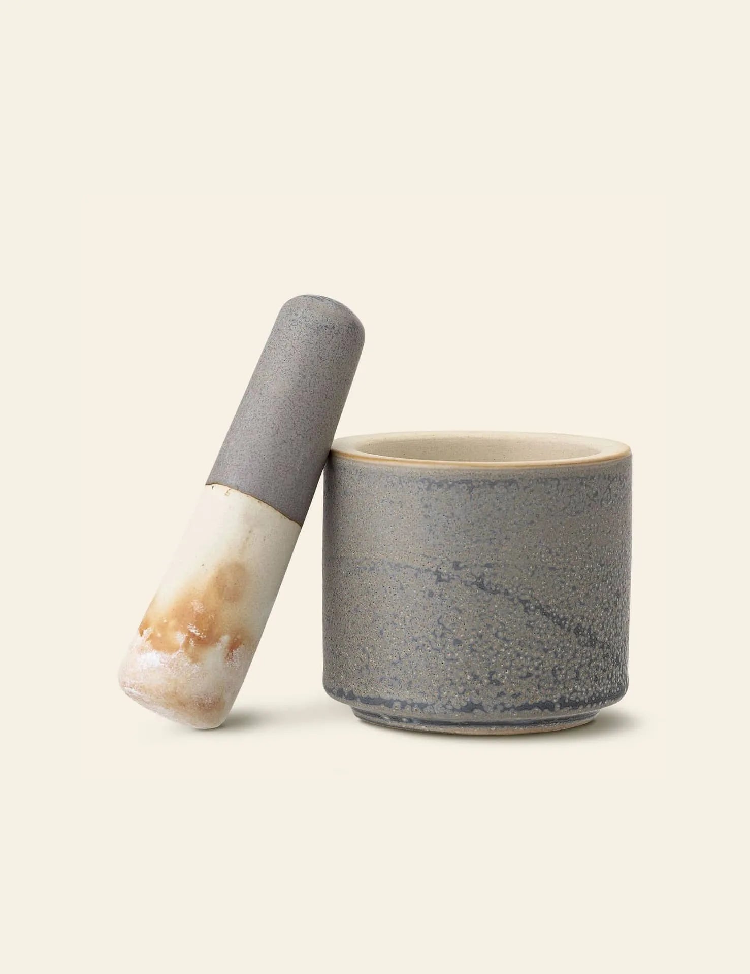 The Bloomingville Kendra Mortar & Pestle features a smooth matte grey finish with beige-brown accents, ideal for grinding herbs and spices. The pestle rests neatly on the mortars rim, showcasing Bloomingville’s elegant design.