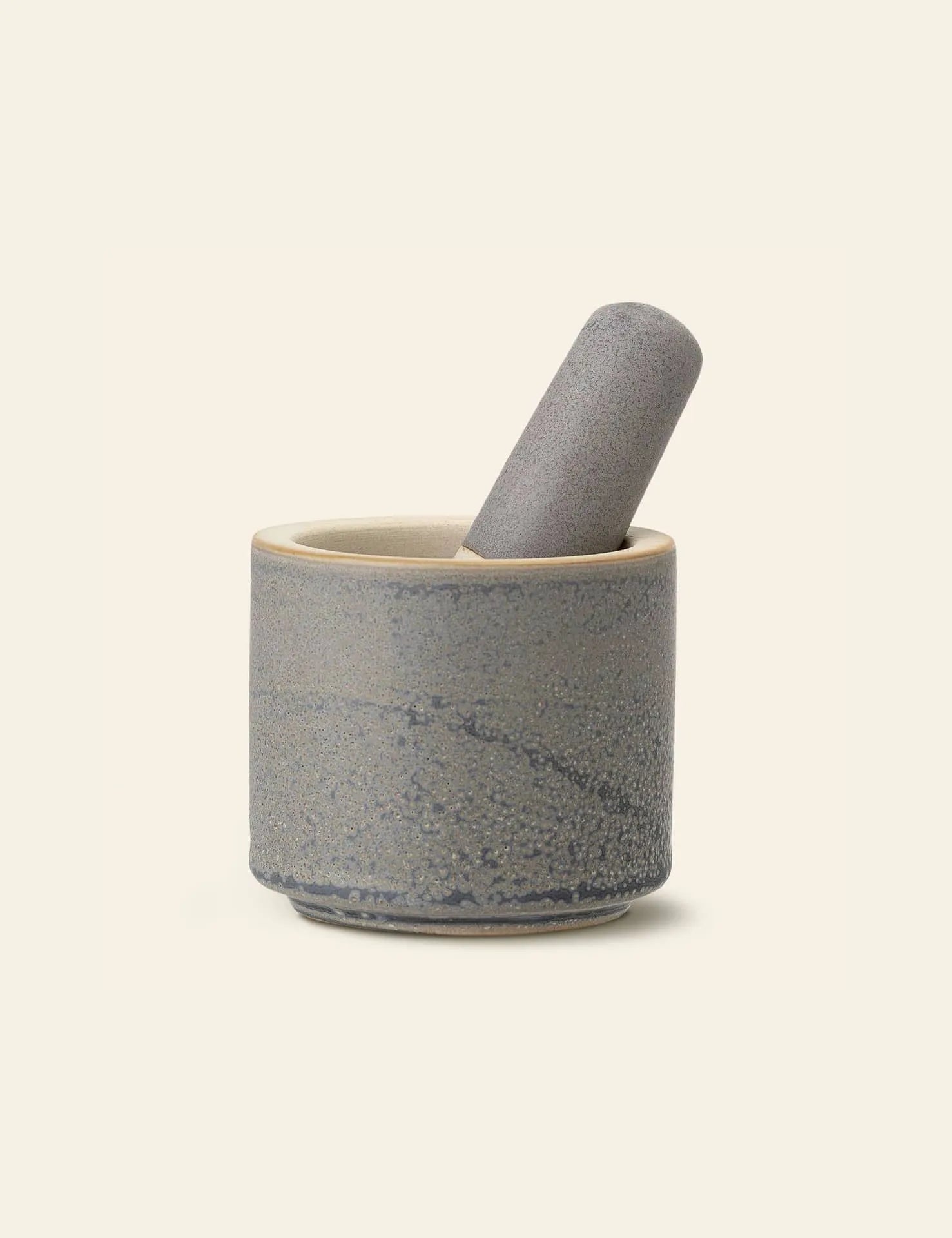 The Bloomingville Kendra Mortar & Pestle features a textured, speckled gray ceramic design. The pestle rests inside the upright mortar, perfect for grinding herbs or spices. Simple and modern, it sits on a plain, light background.