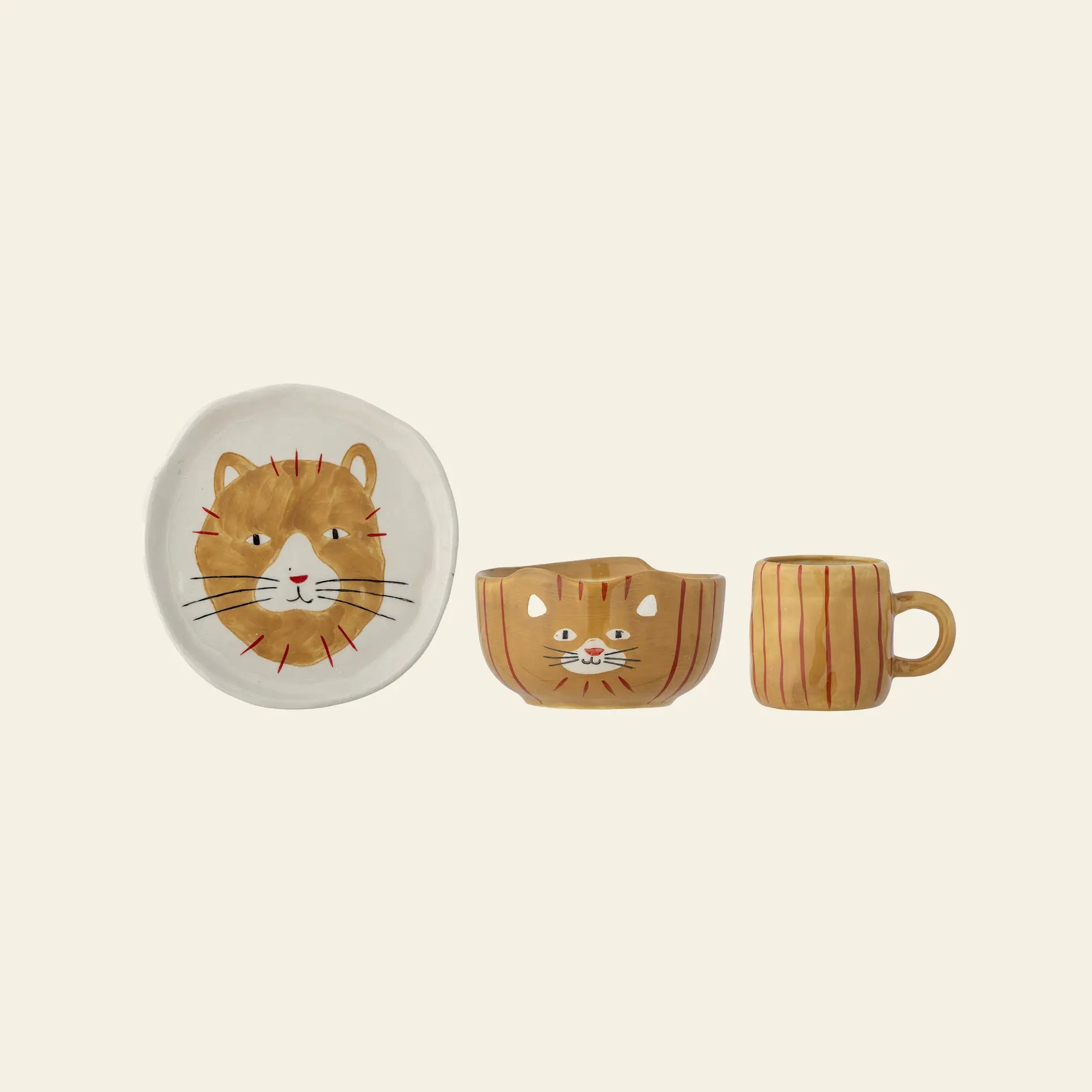 The Bloomingville Kittie Tableware by Bloomingville features three ceramic pieces—a round plate, a cat-ear bowl, and a mug—each with brown and orange stripes, whiskers, and a cute cat motif.