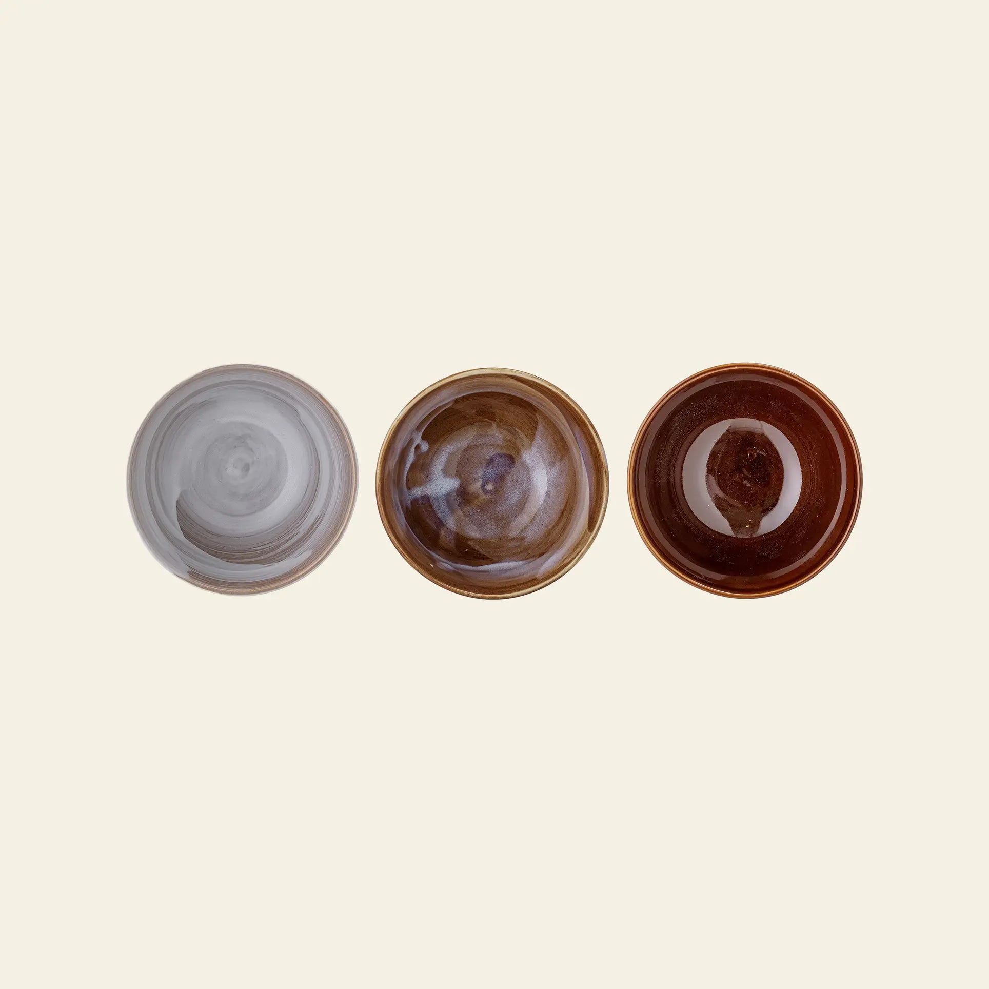 The Bloomingville Lotus Bowl Set of 3 features round stoneware bowls with gray, brown, and reddish-brown marbled patterns, inspired by traditional Asian dishes, arranged on a light beige background.