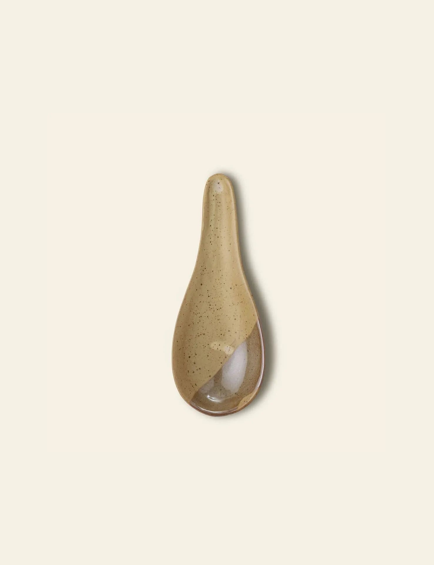 The Bloomingville Masami Spoon rest by Bloomingville features a speckled beige glaze and an elongated oval shape, ideal for keeping your kitchen tidy while cooking. Photographed on a plain, light background.