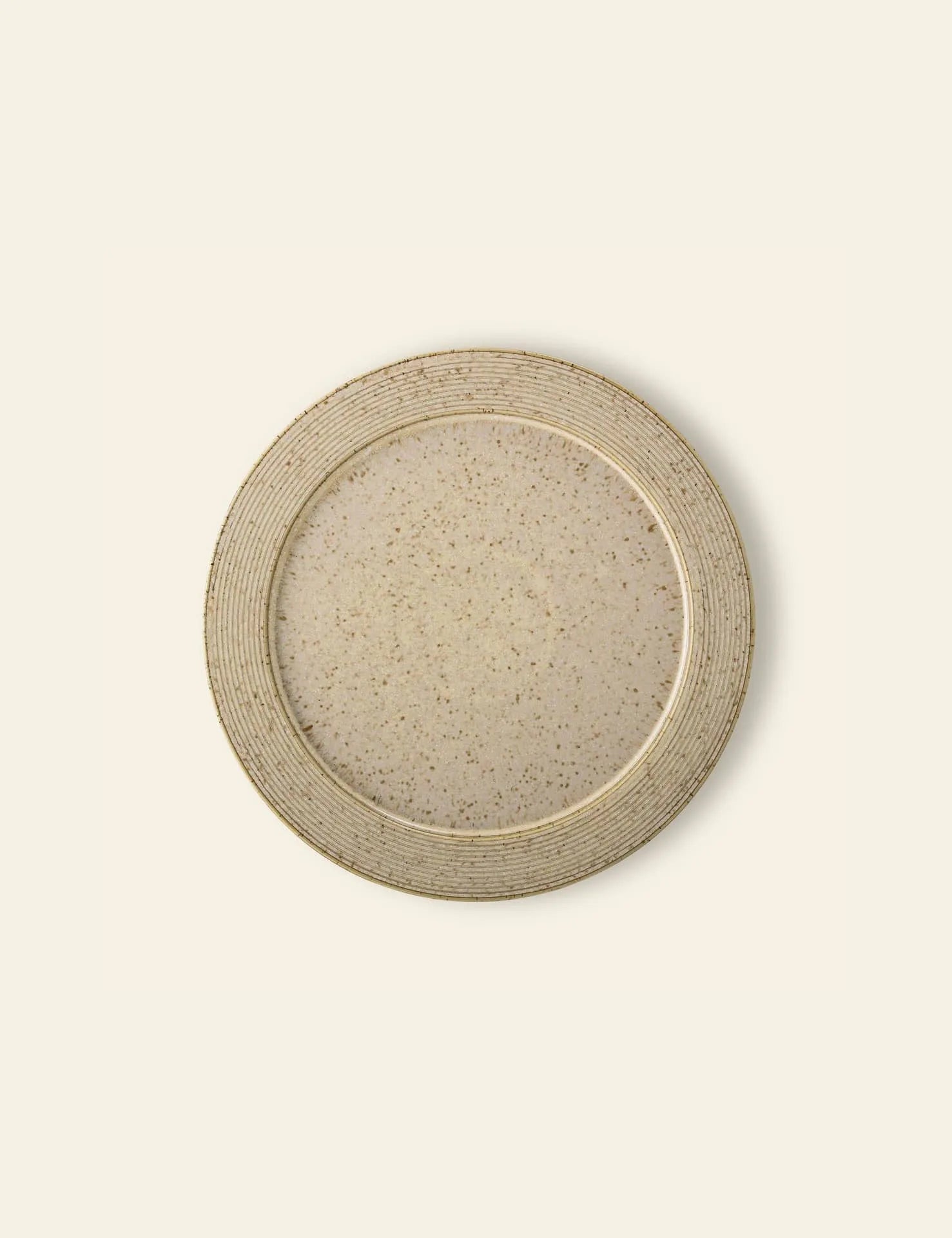 The Bloomingville Nugga Plate by Bloomingville is a round, beige stoneware plate with a speckled pattern and ridged rim—an ideal choice for serving outdoor meals on a light, neutral backdrop.