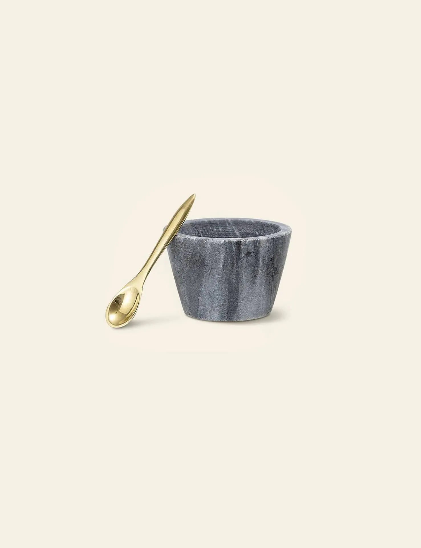 The Bloomingville Rosamynthe Salt Jar with Spoon, a small round gray marble bowl, appears beside its gold spoon on a plain light beige background.