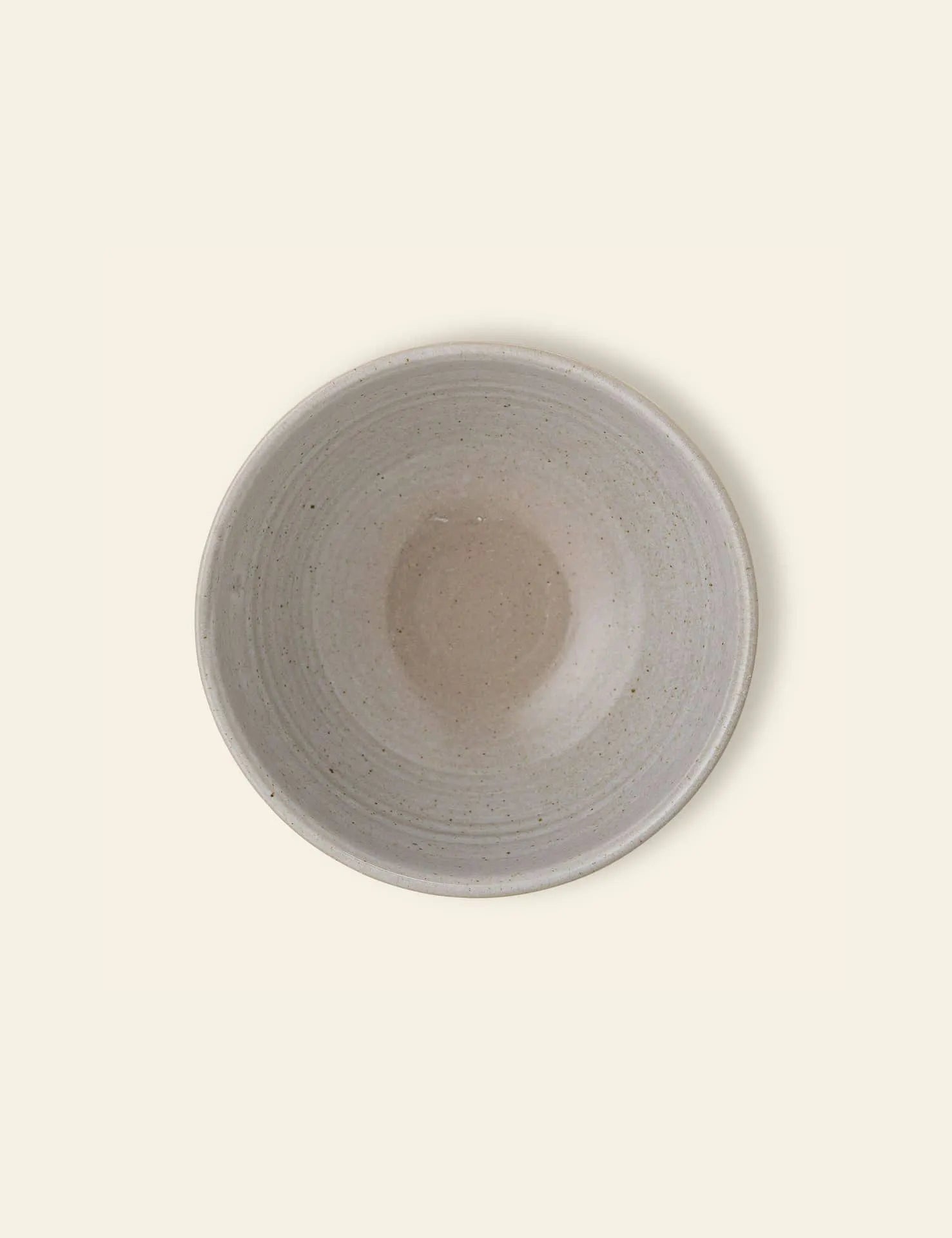 The Bloomingville Taupe Bowl by Bloomingville is a round, shallow natural stoneware bowl with a durable, smooth, speckled light beige glaze, shown from above on a pale background.