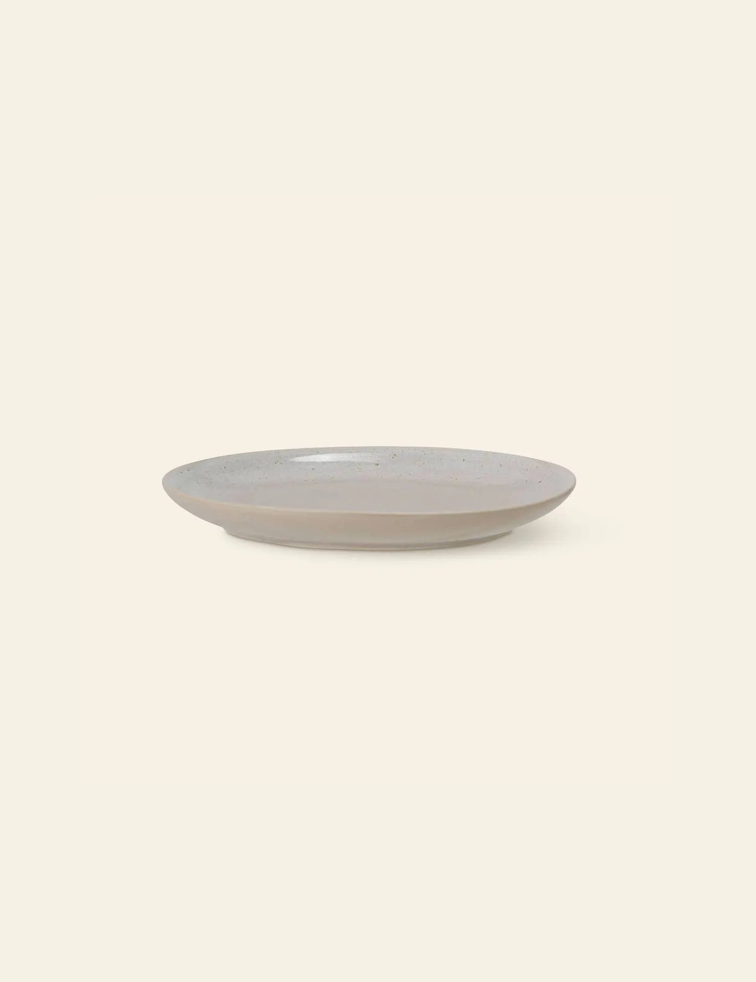 The Bloomingville Taupe Plate is a simple, round stoneware piece with a slightly raised rim, featured in light taupe against an off-white background.