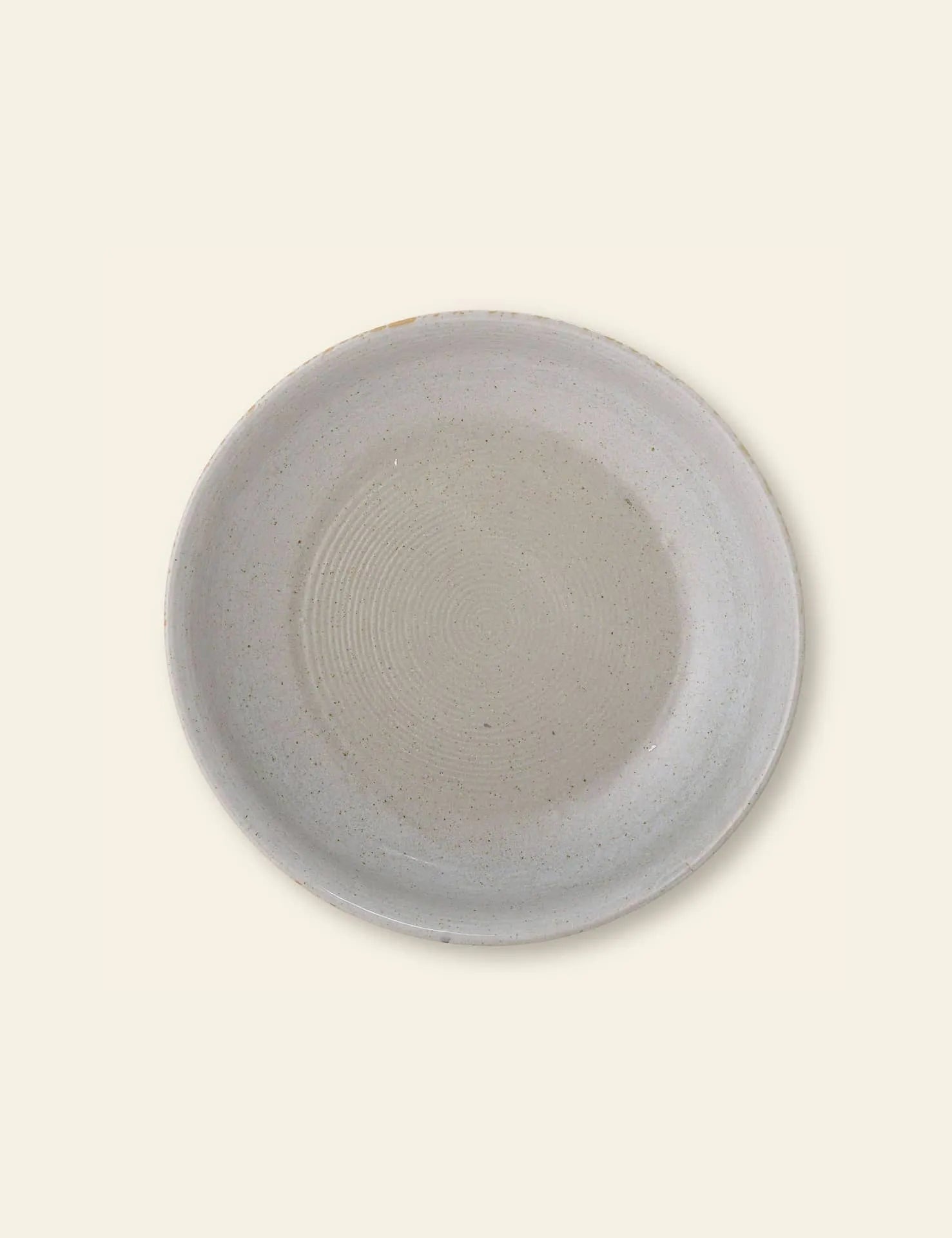 The Bloomingville Taupe Serving Bowl by Bloomingville features a simple round design with a light gray finish and subtle speckles, making it a stylish addition to any kitchen collection. Shown on a plain off-white background.