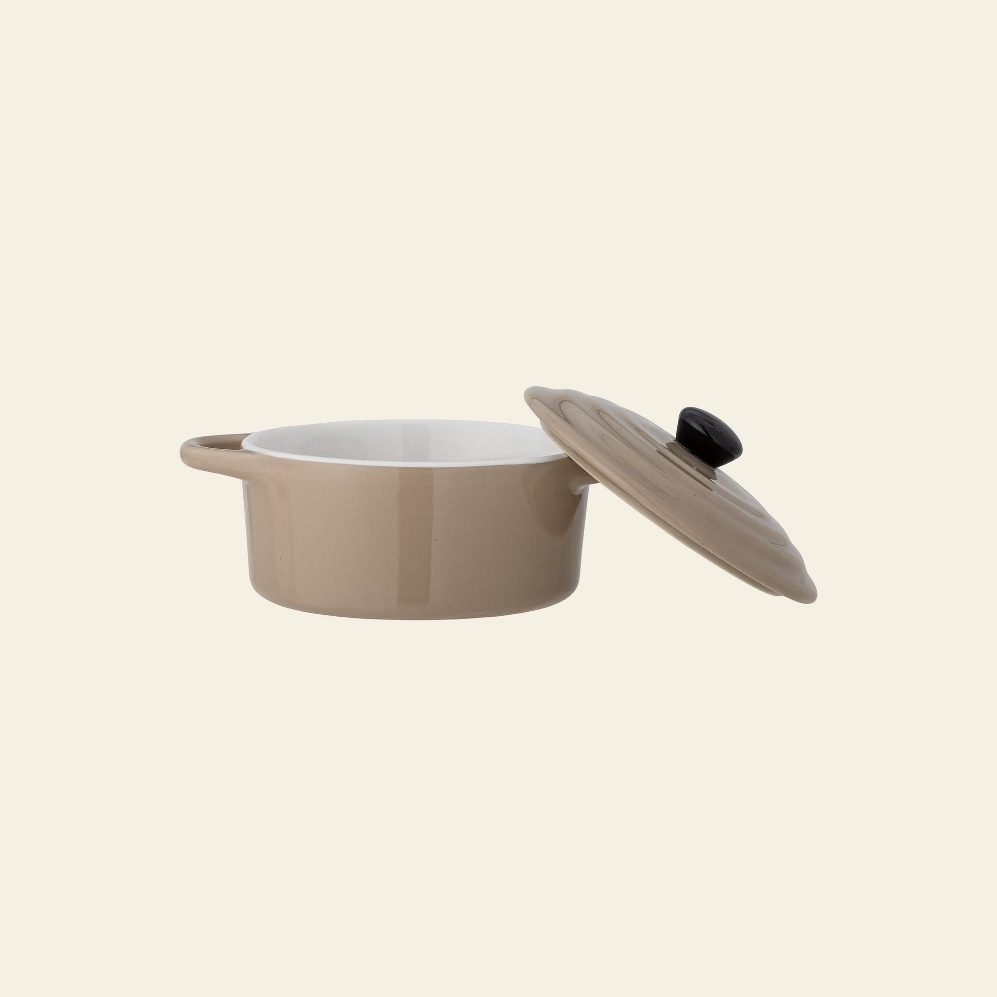 The Bloomingville Thanos Oven Dish w/Lid by Bloomingville features beige stoneware with a white interior. Shown with its lid tilted, it’s ideal for baking casseroles or serving dishes, and makes a stylish addition to any kitchen.