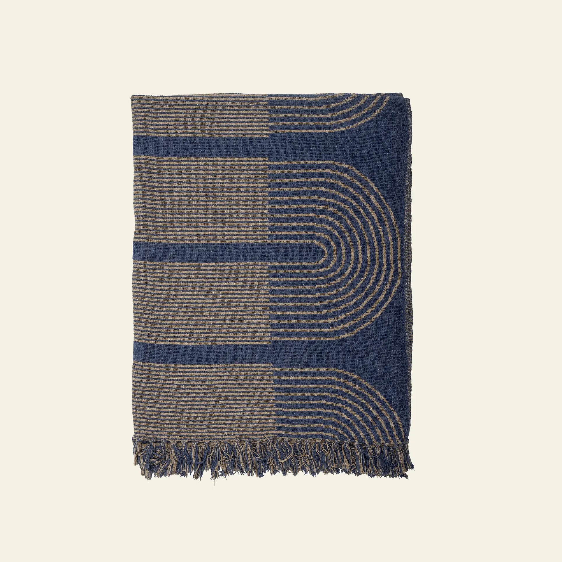 The Bloomingville Tiffanie Throw by Bloomingville is made from soft cotton, featuring a navy blue and tan graphic curved line pattern with fringed edges, shown on a plain light background.