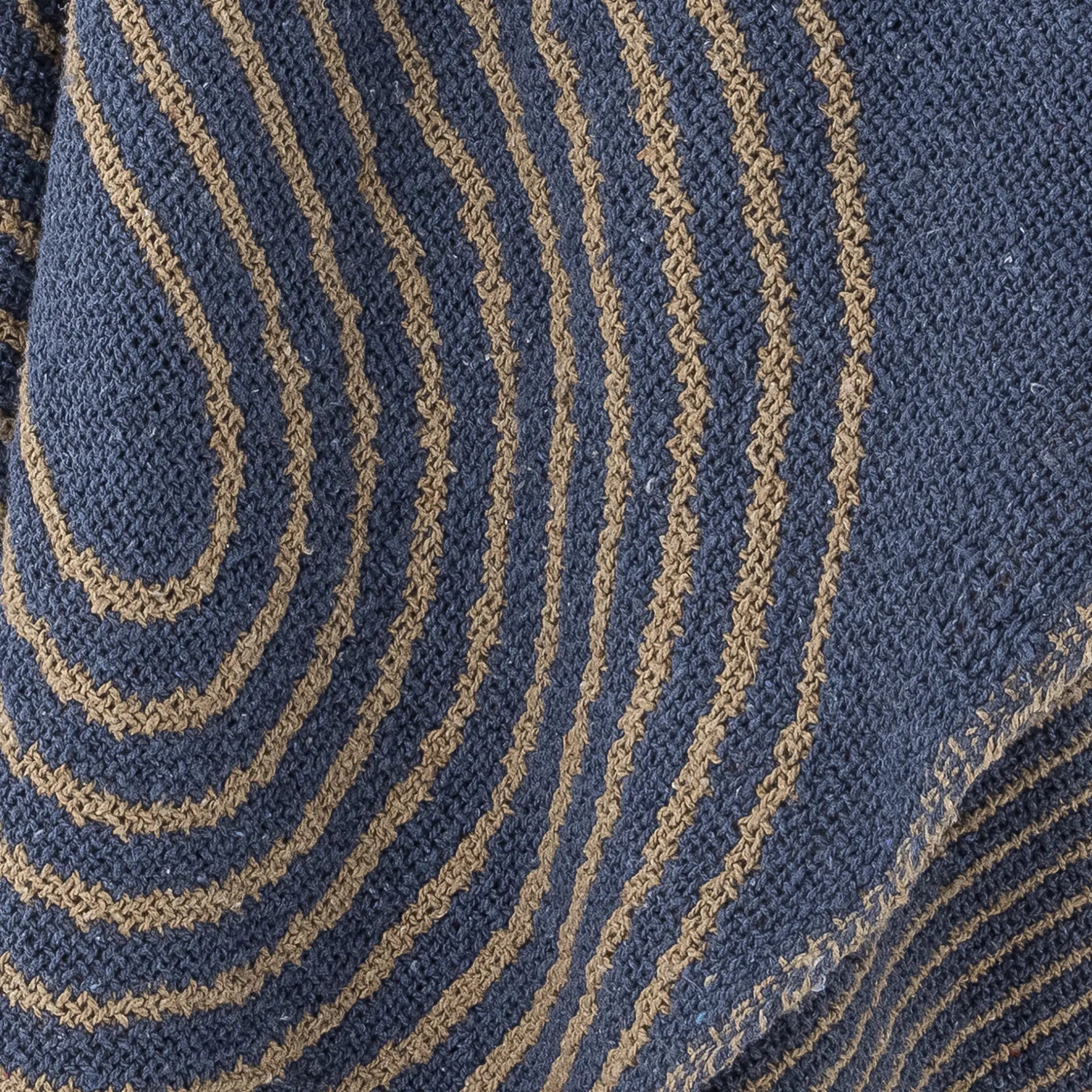 Close-up of blue cotton fabric with wavy, parallel tan stripes forming a graphic, textured pattern inspired by the Bloomingville Tiffanie Throw.