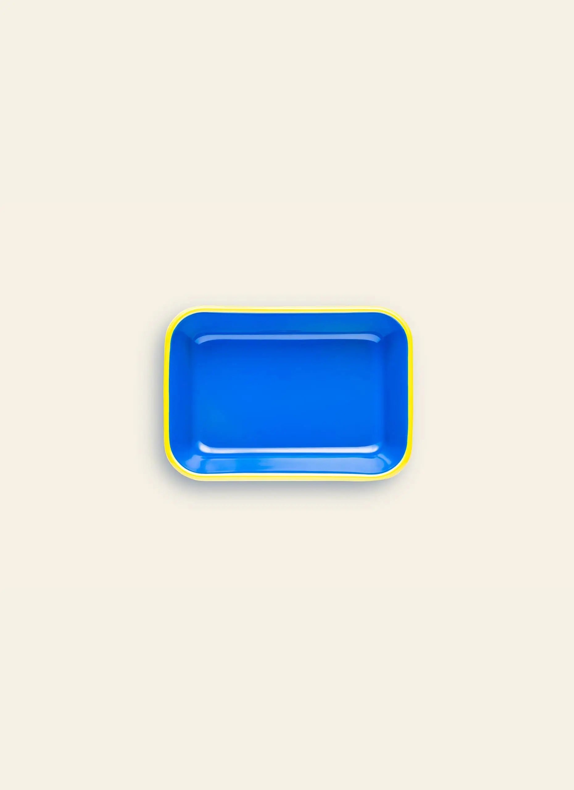 The Bornn Enamelware Colorama Baking Dish, Medium, features a rectangular blue design with rounded corners and a slim yellow rim, reflecting the brands handmade enamelware craftsmanship against a light beige background.