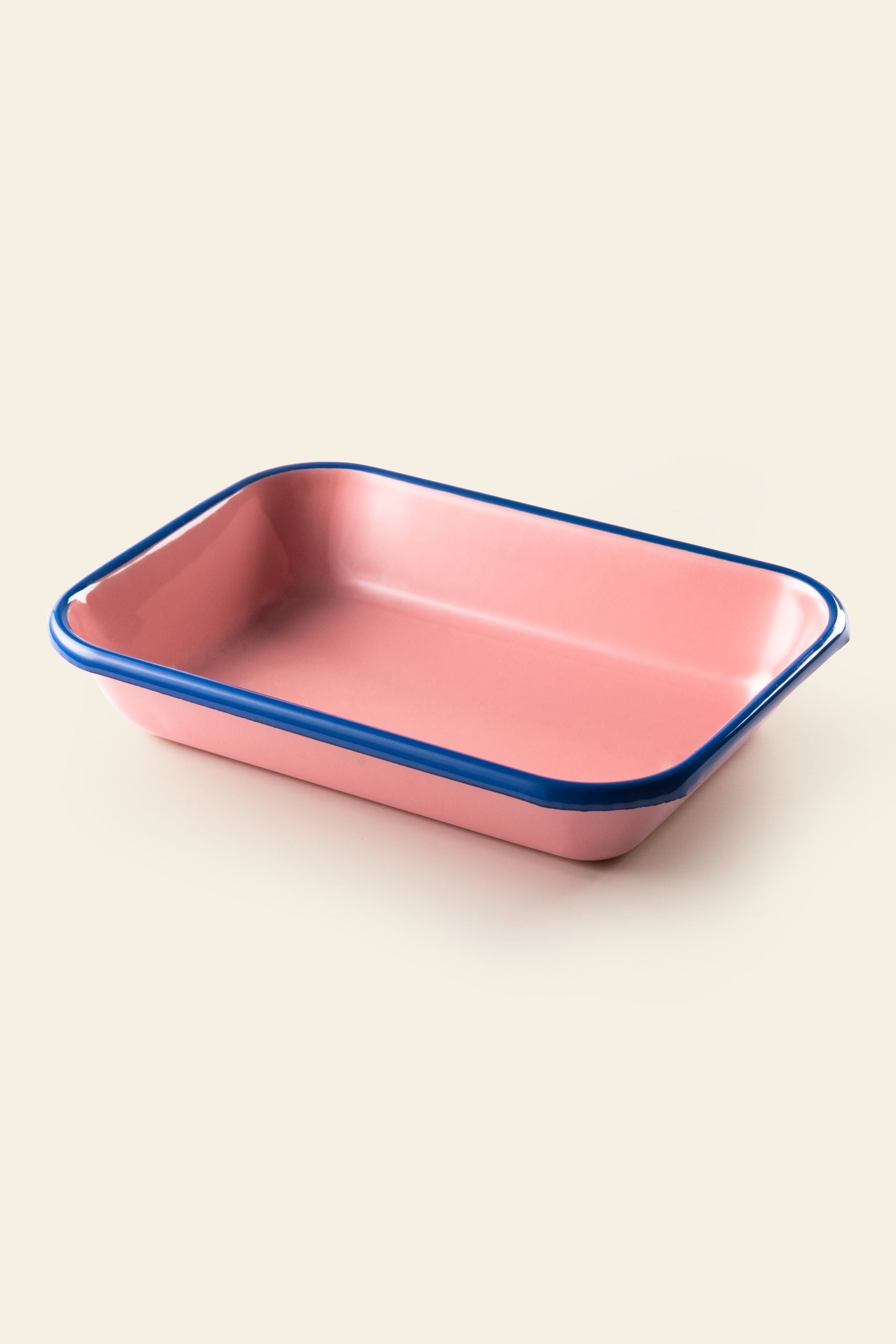 The Bornn Enamelware Colorama Baking Dish, Medium, by Bornn Enamelware, is displayed empty in pink with a blue rim against a plain light background.