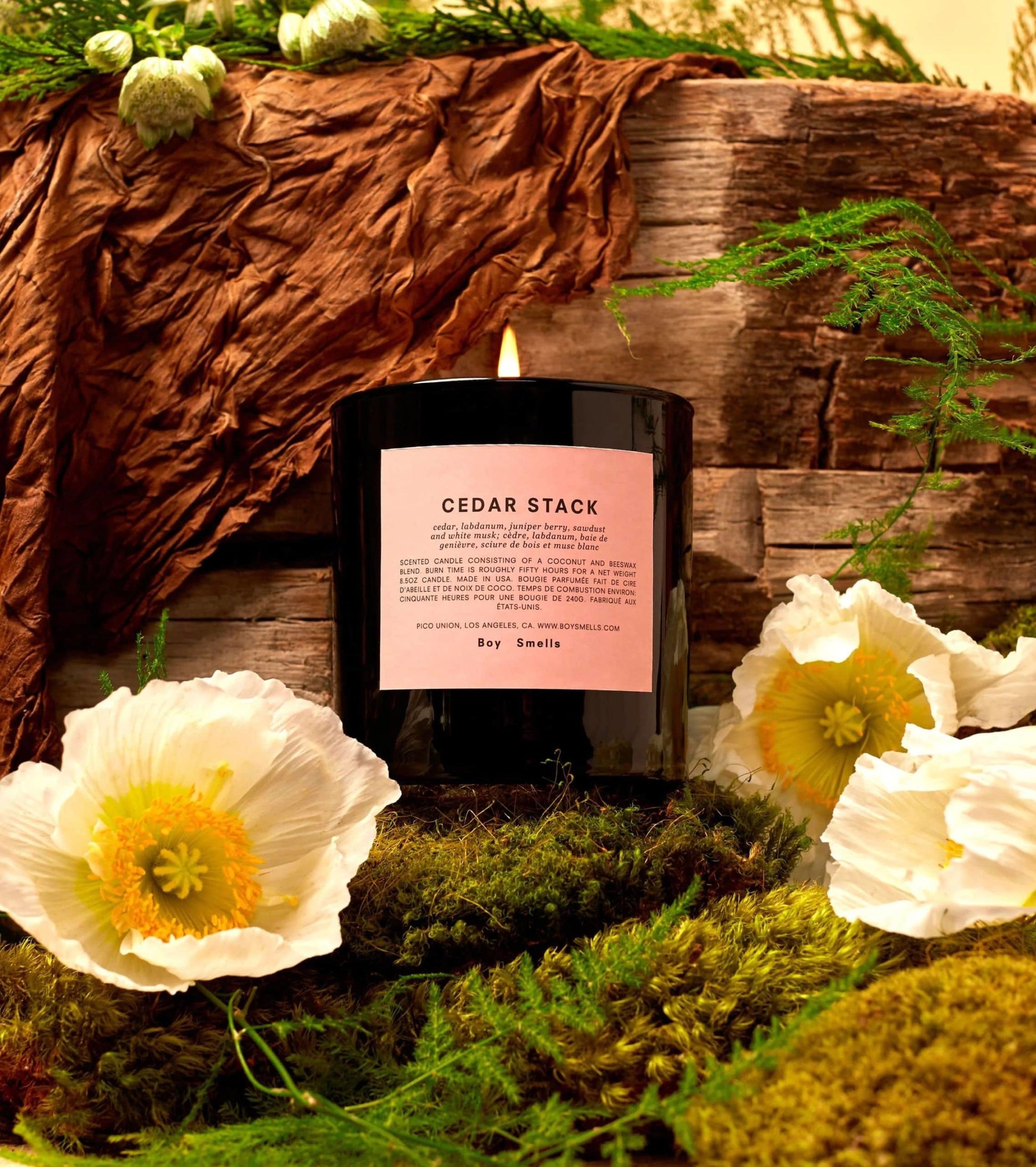 The Boy Smells Cedar Stack Scented Candle 8.5oz fills your space with a blend of white florals, green moss, and rustic wood, creating a warm, earthy ambiance with its unique fragrance.