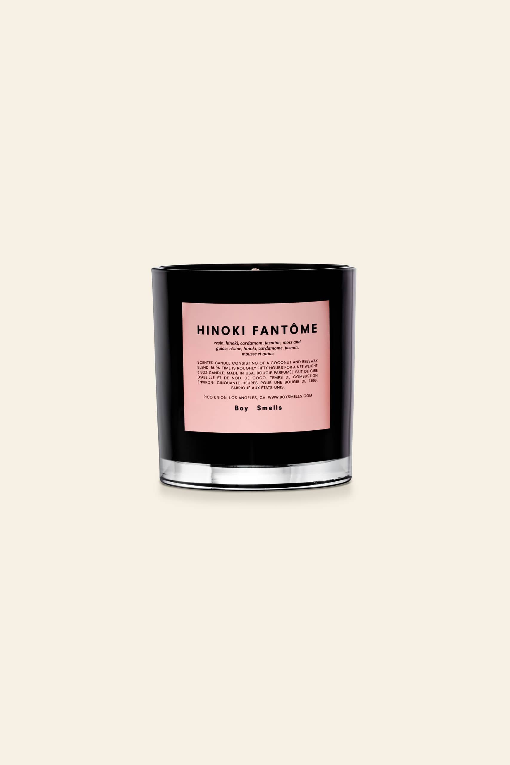The Boy Smells Hinoki Fantôme Scented Candle 8.5oz features a black glass jar with a pale pink label, capturing Japanese cypress notes, and is showcased against a plain beige background.