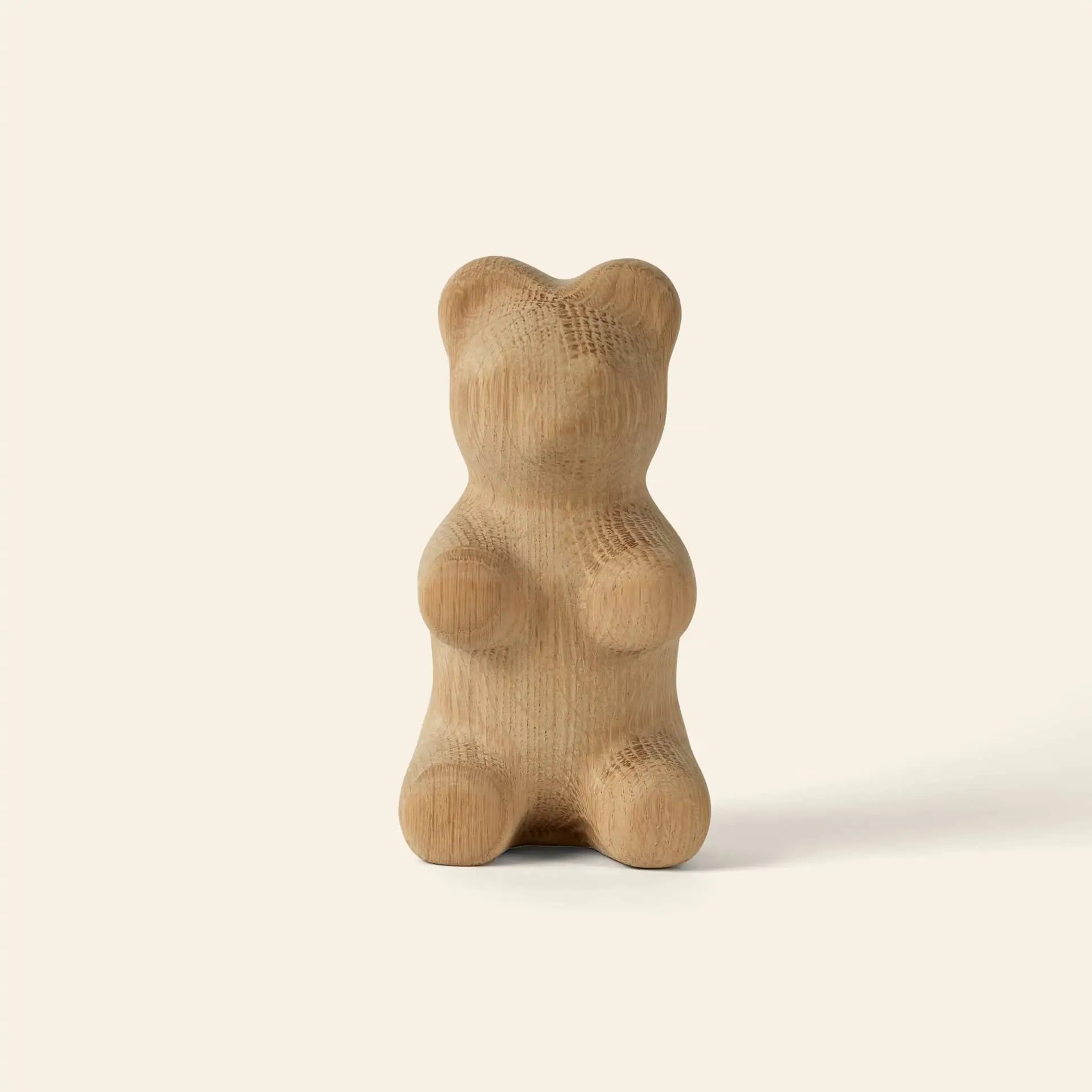 The Boyhood Gummy Bear Small by Boyhood is a smooth wooden sculpture with soft, rounded curves and no facial details, shaped like a classic candy bear and displayed against a plain, light beige background.