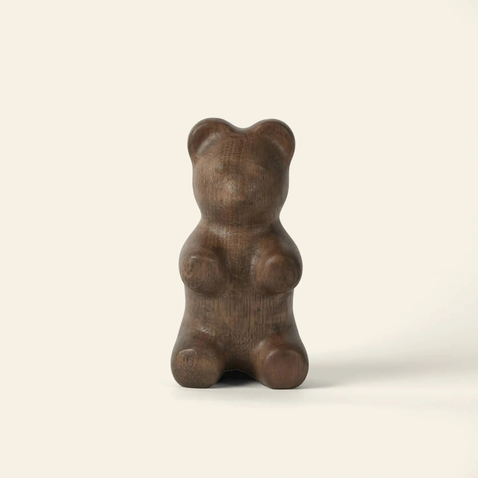 The Boyhood Gummy Bear Small by Boyhood is a smooth, dark brown sculpture shaped like a gummy bear, standing upright against a light backgroundโan irresistible piece of eye candy.
