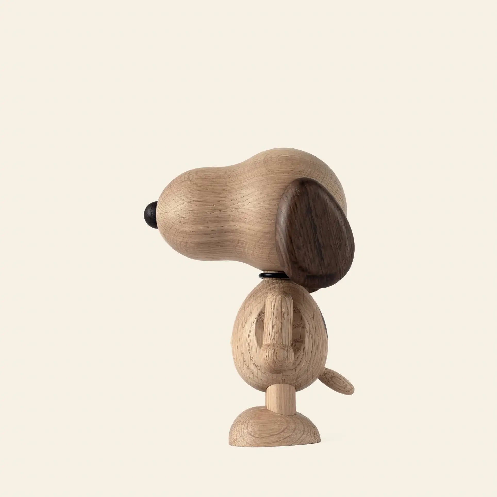 The Boyhood Snoopy Small by Boyhood is a minimalist wooden figurine with a large head, dark brown ears, and a round tail, shown in profile facing left against a plain light background.