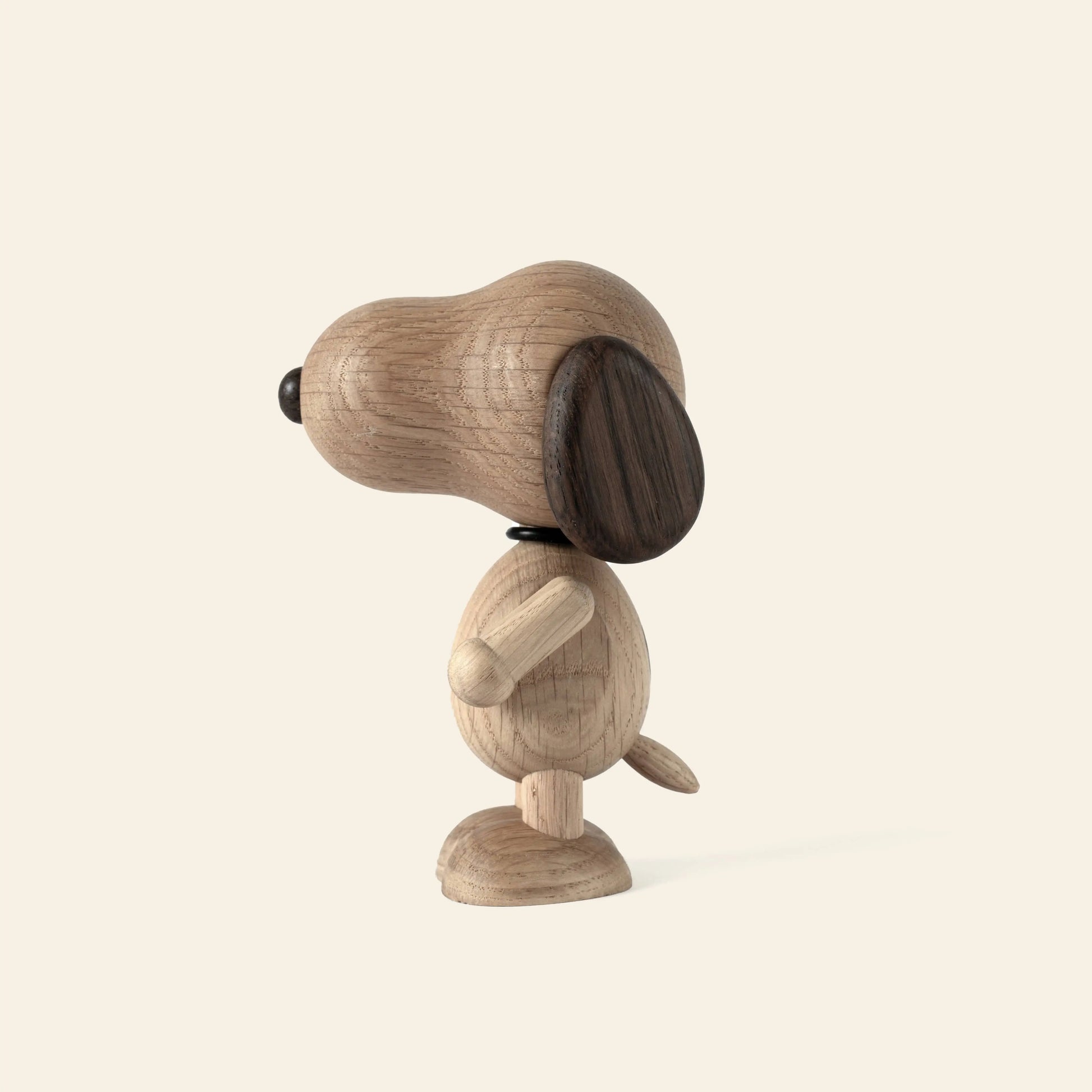 The Boyhood Snoopy Small by Boyhood is a wooden figurine with a large oval head, dark ear, round body, and small tail. It stands upright facing left on a light background—ready to nap atop his iconic doghouse.