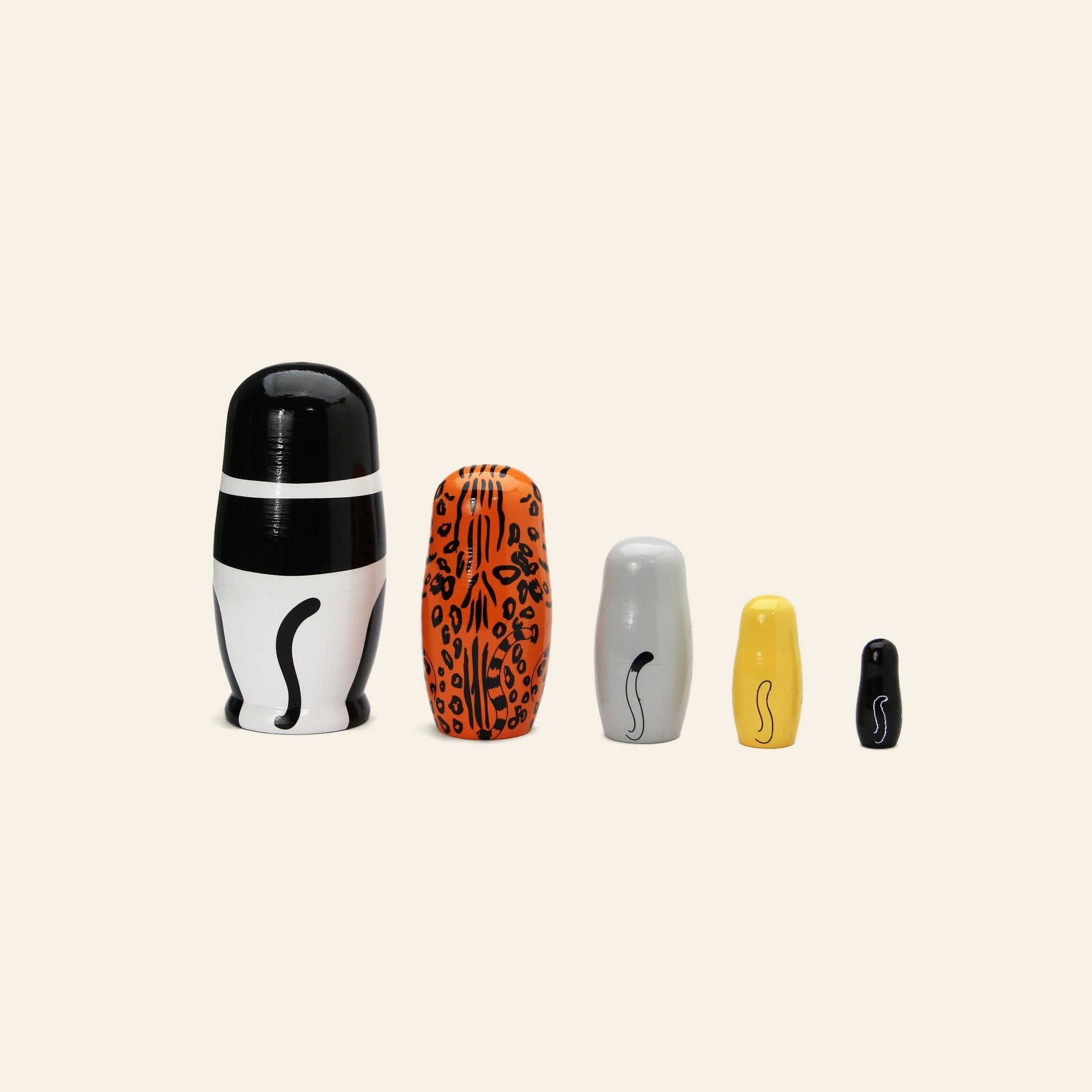 DETAIL Feline 5 Nesting Dolls by DETAIL feature five cat-themed wooden dolls, each with unique patterns—black and white, orange spots, gray, yellow, and solid black—perfect for cat lovers and displayed on a light beige background.
