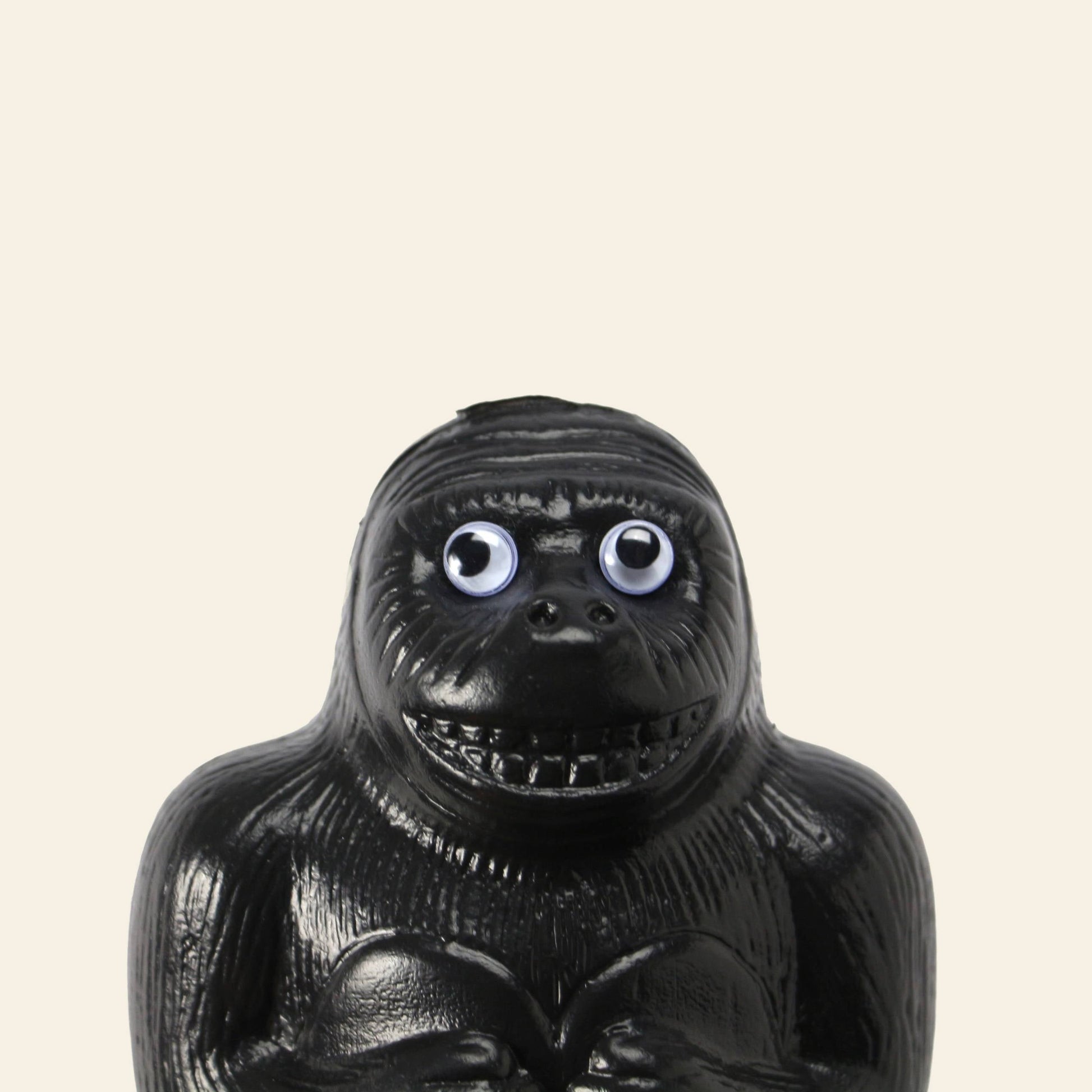 The DETAIL Gorilla Bank Small by DETAIL is a black figurine with large googly eyes and a toothy grin, set against a light beige background—a fun decorative accent for any room.