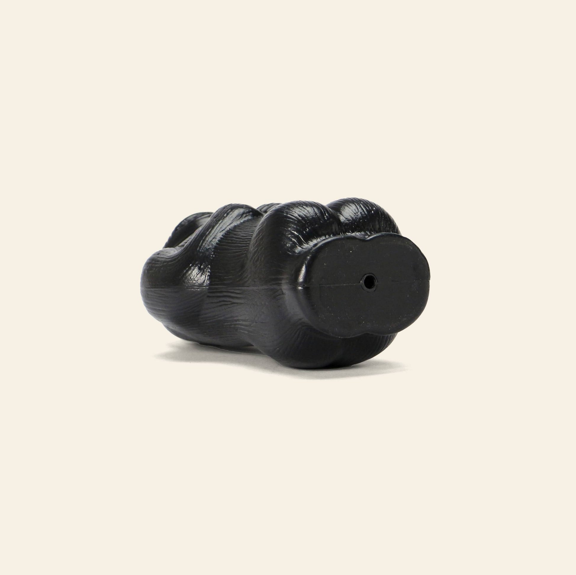 The DETAIL Gorilla Bank Small by DETAIL is a black, paw-shaped decorative piece with a hole in its base, resembling an animal or gorilla paw, and is showcased on a simple light background.