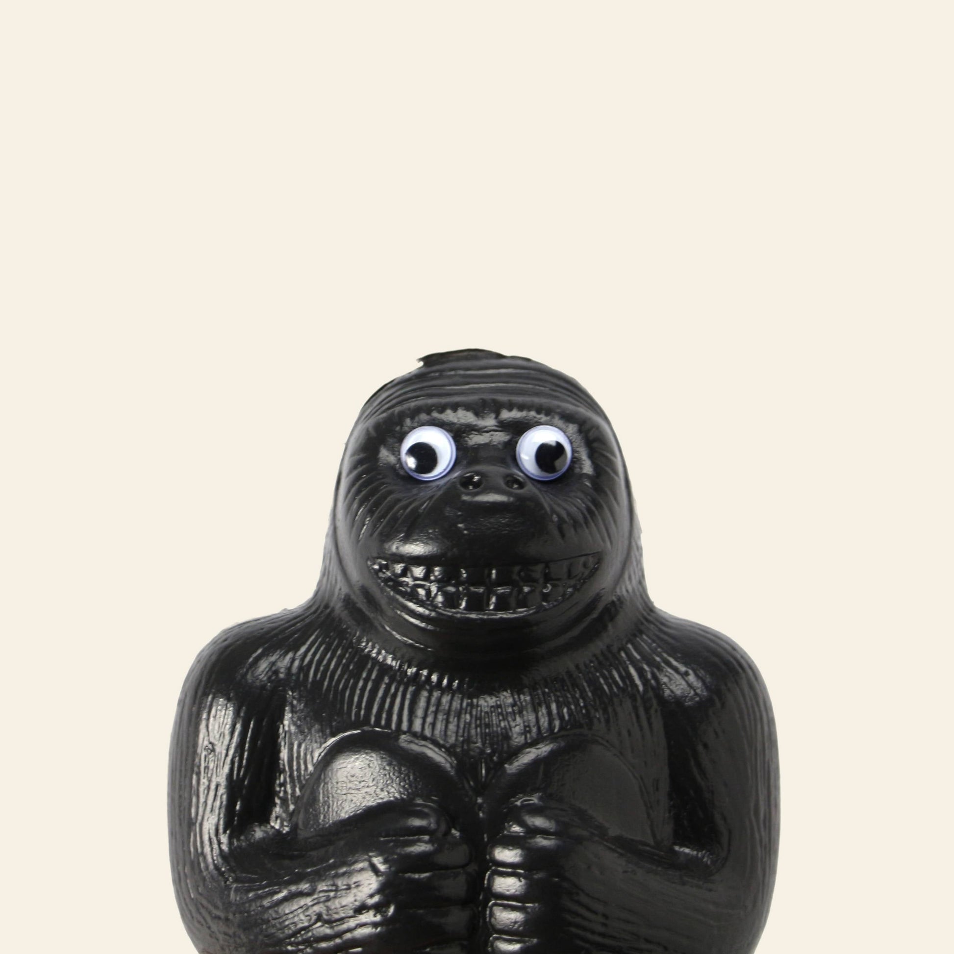 The DETAIL Gorilla Bank Small by DETAIL is a playful black plastic figurine with exaggerated features and googly eyes, standing upright against a light beige background—perfect as a fun decorative piece.