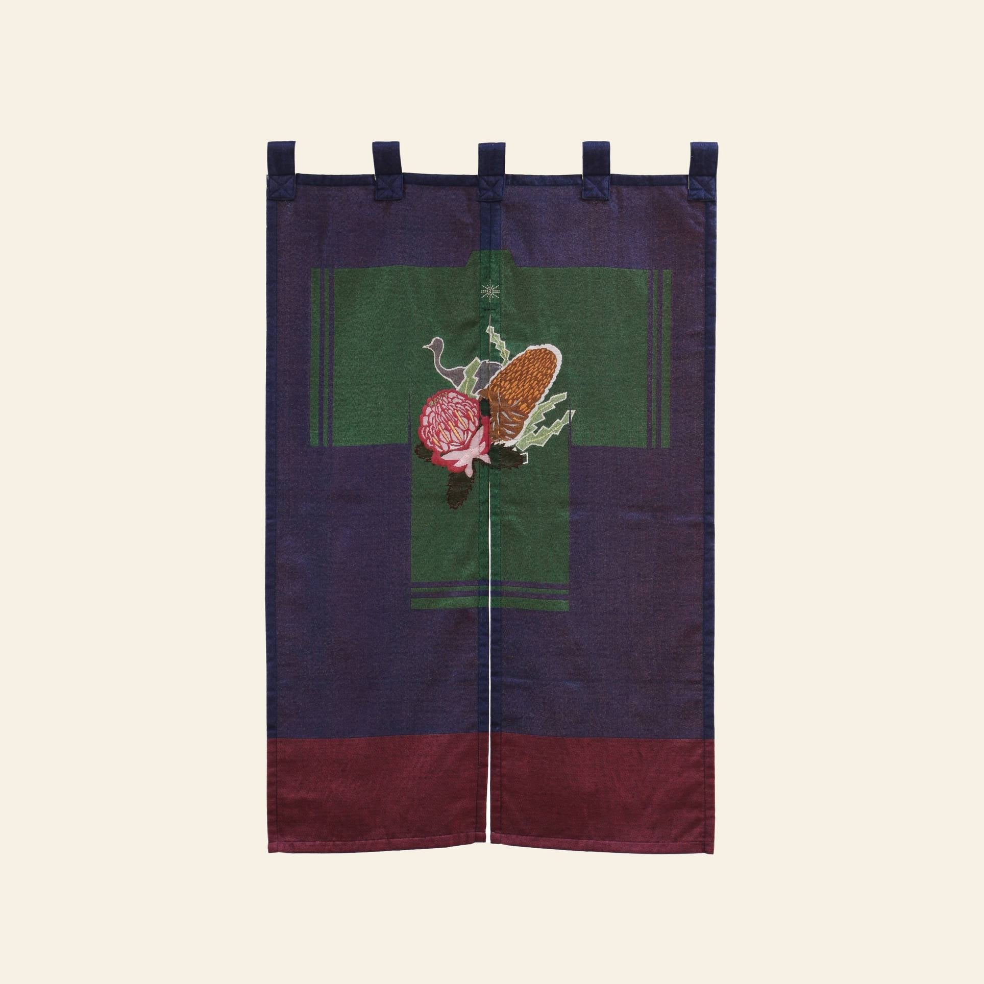 The DETAIL Noren Curtain by DETAIL features top loops, a central green cross, and embroidered pomegranate and pine cone motifs inspired by kimono patterns, with deep blue and burgundy hues for a rich, plant-themed design.