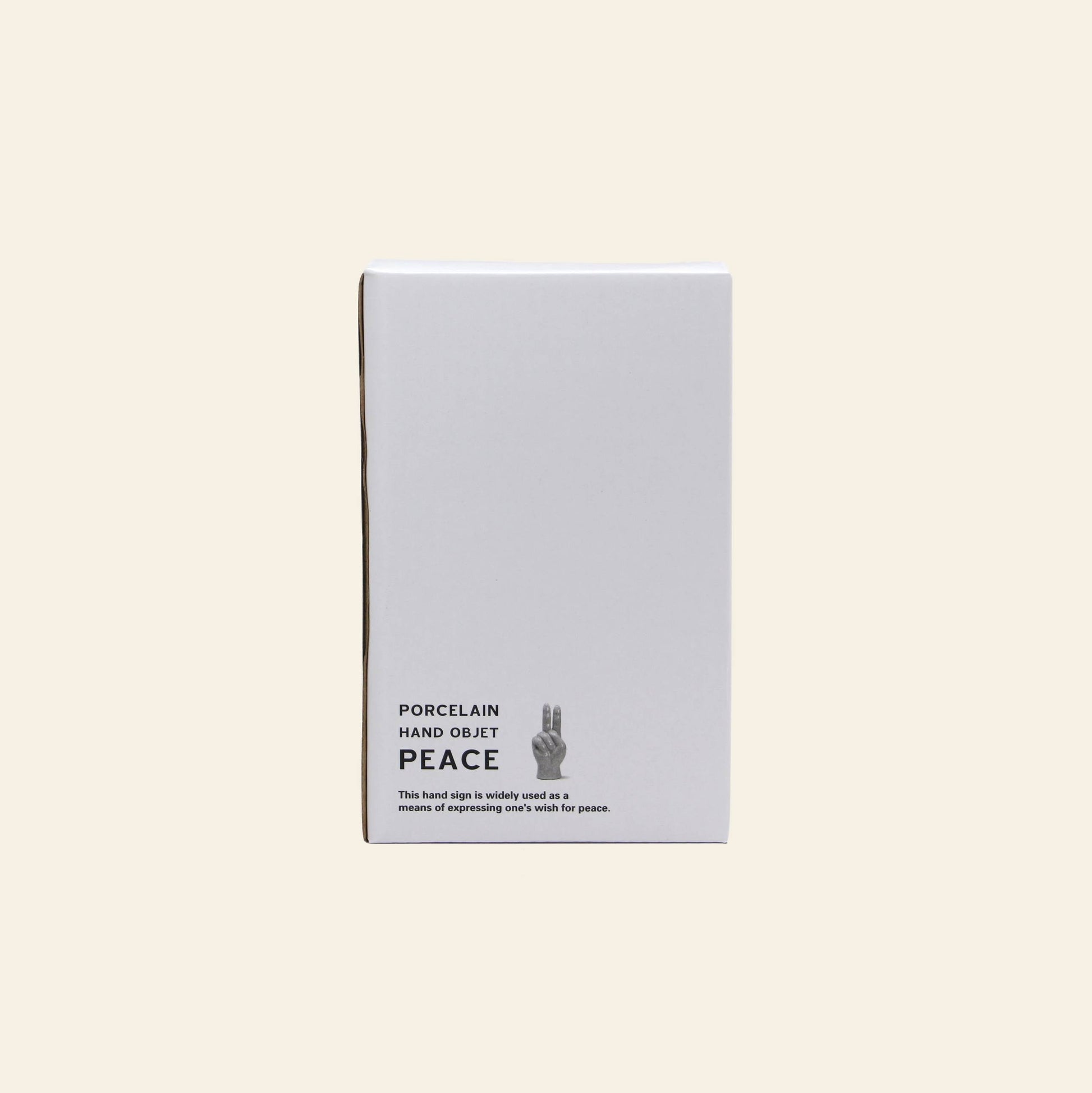 A white rectangular box labeled DETAIL Porcelain Hand Peace by DETAIL shows an illustrated hand making a peace sign, ideal as a ceramic decor piece or accessory stand, set against a plain beige background.