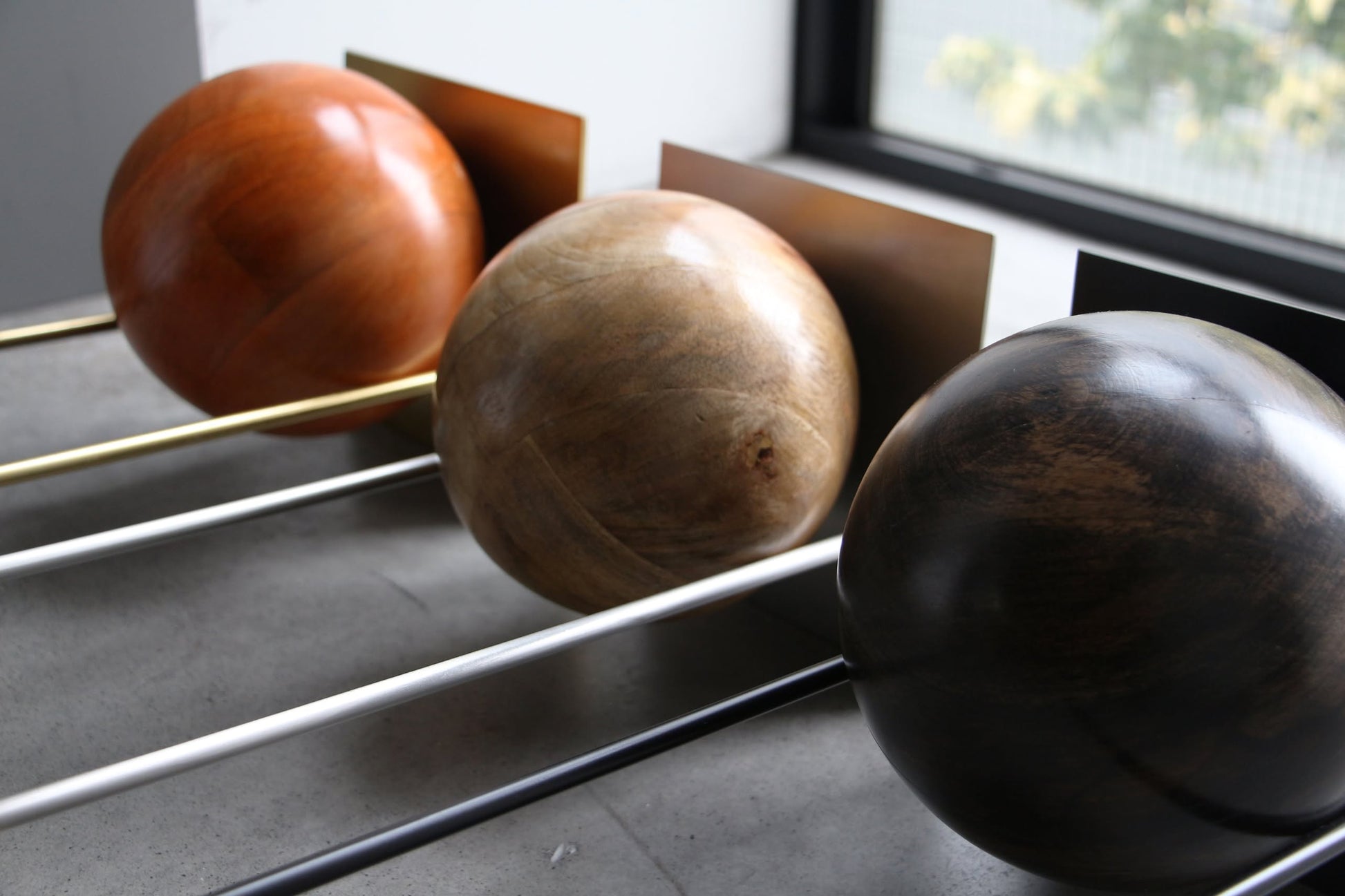 The DETAIL Slope Bookend by DETAIL features three large wooden spheres in brown tones on metal rods, offering a minimalist and sculptural accent for your space.